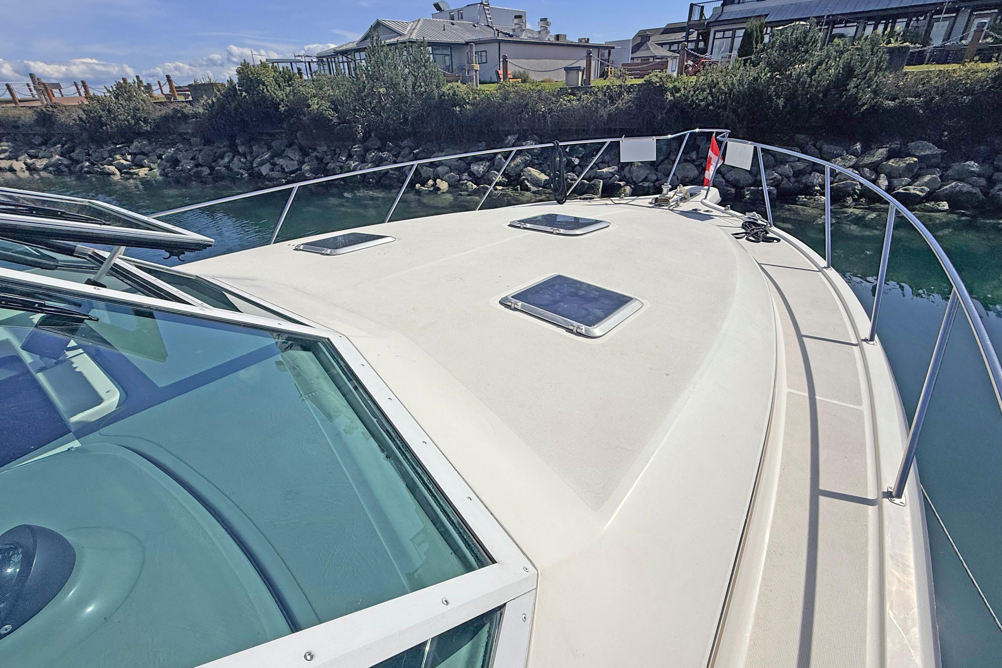 1996 Tiara 3700 Open Hardtop boat docked near rocky shoreline.