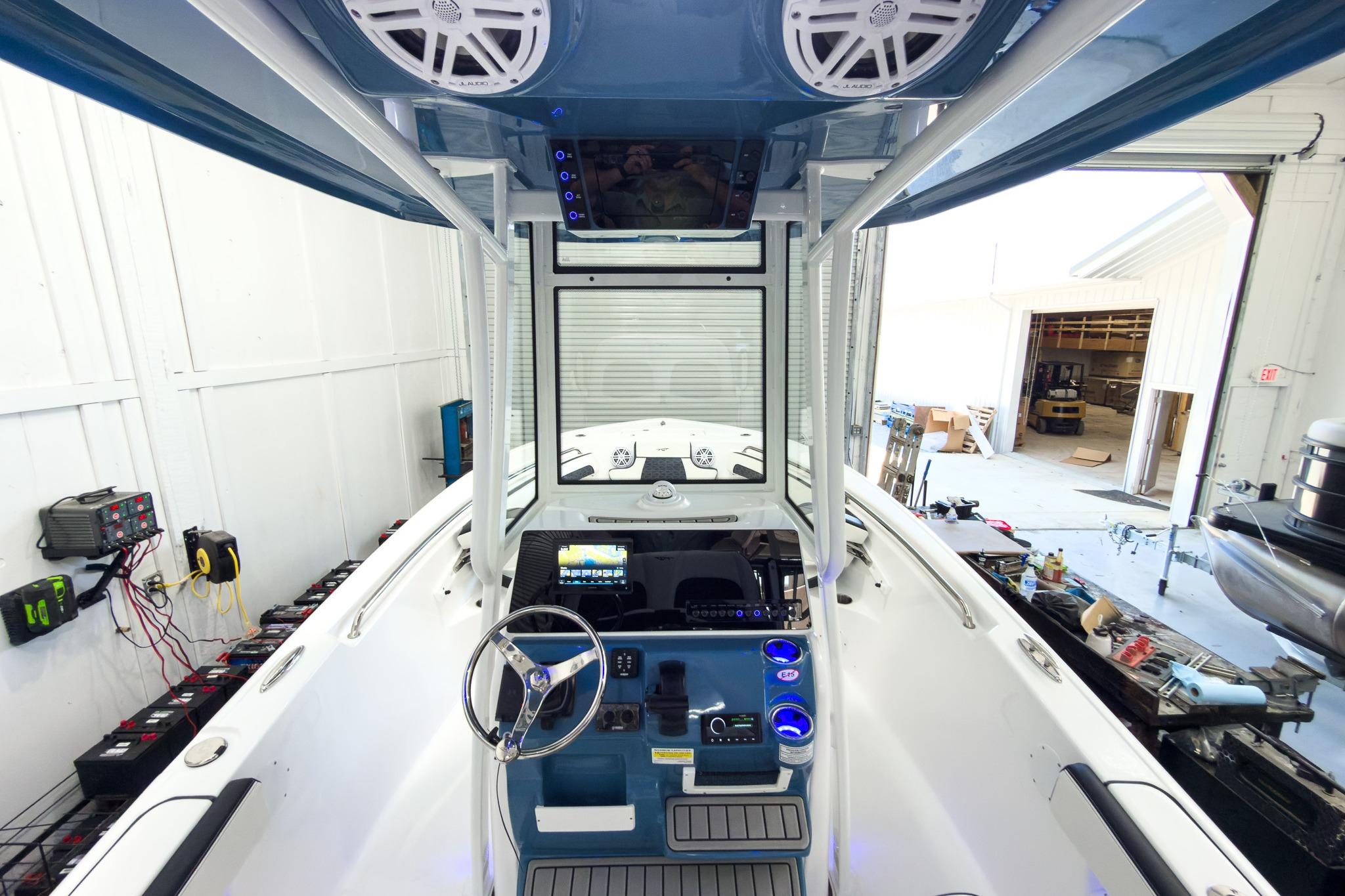 The image shows the cockpit of a Tidewater 220 LXF boat in a workshop. It features modern electronics and speakers.