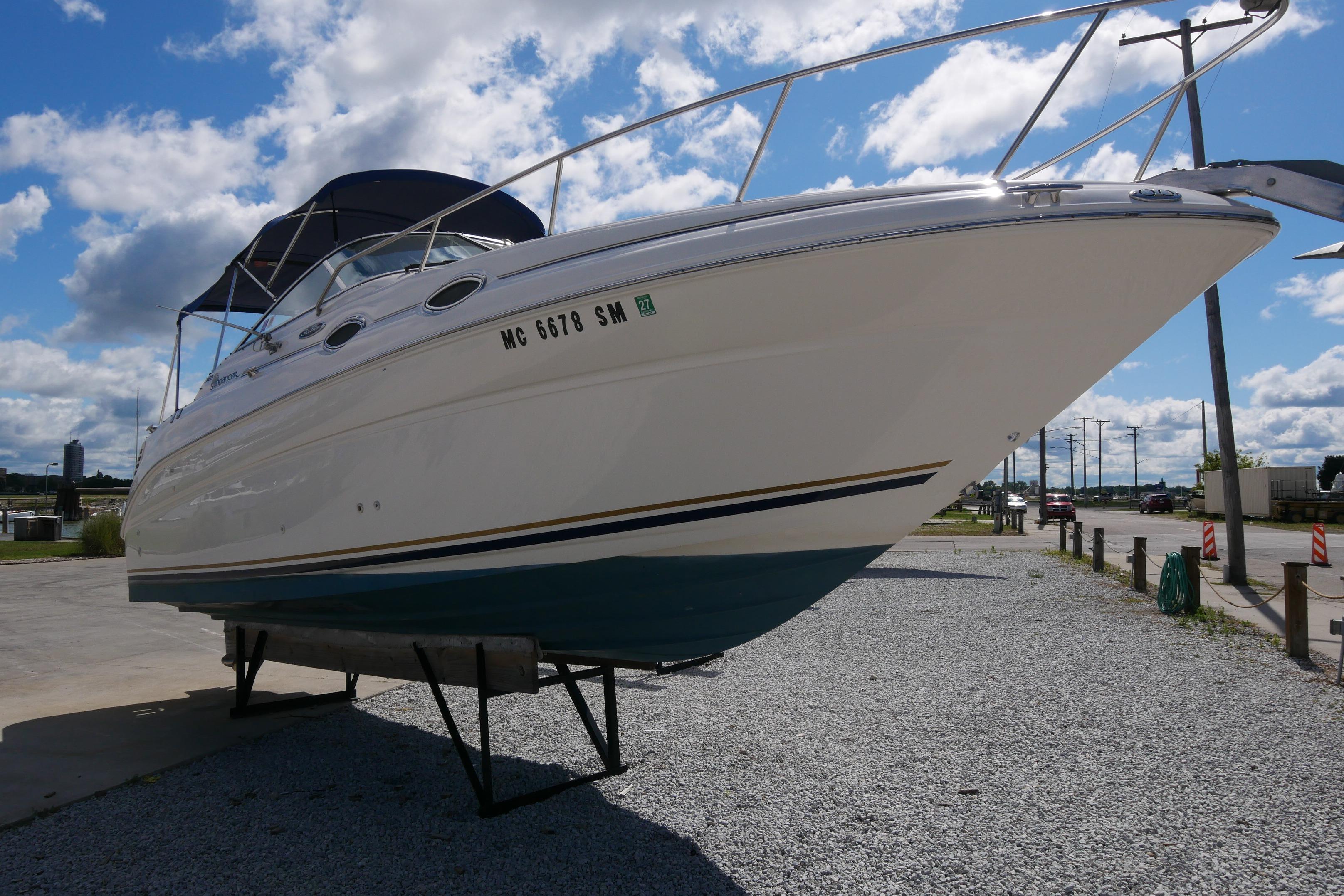 2003 Sea Ray 260 Sundancer boat on dry dock under a clear blue sky.