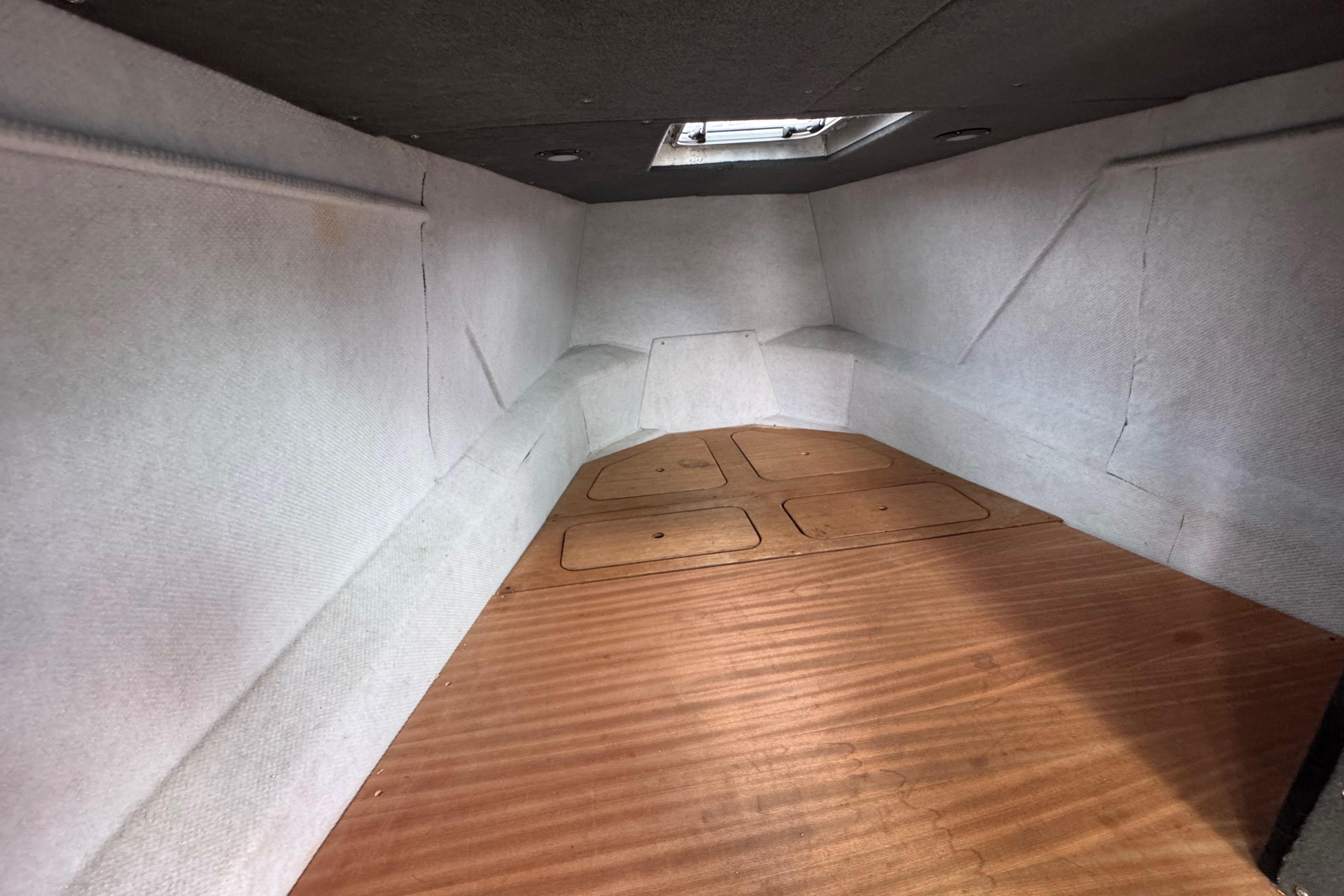 Interior cabin of a 2003 ACB 30 boat, featuring wooden flooring and white walls.