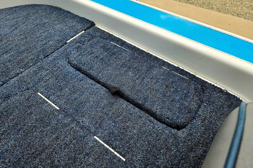 1996 Champion 181 SX boat interior with blue carpet and storage compartment.