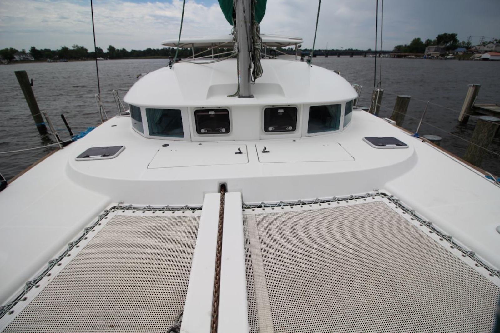 2004 Lagoon 380 catamaran deck view with netting, docked by the water.