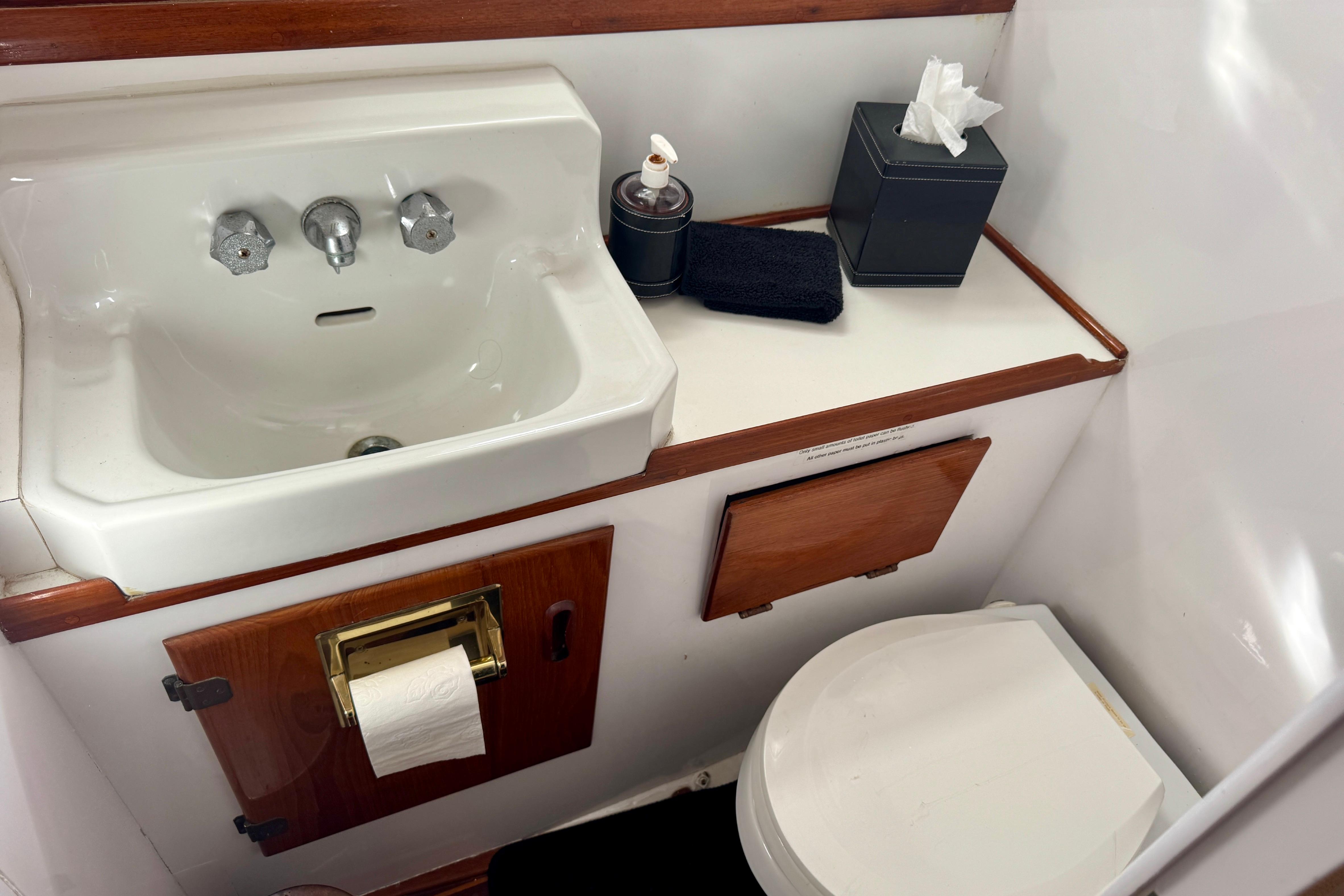 1958 Blanchard Pilothouse bathroom with sink, toilet, and wooden accents.