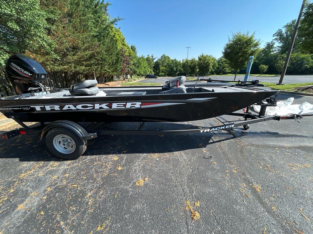 2025 Tracker Panfish 17 boat on trailer, parked outdoors, surrounded by trees.