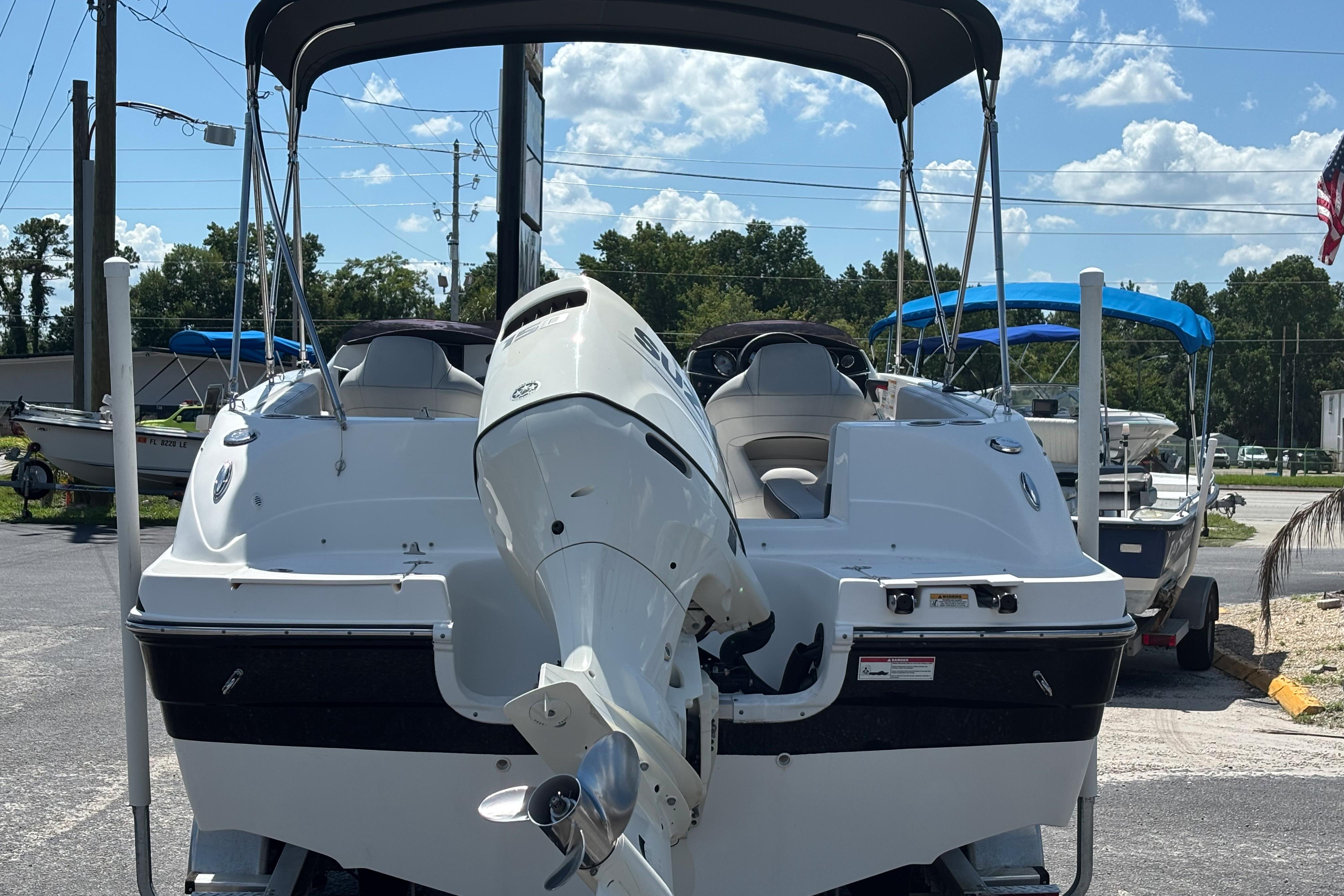 2019 Hurricane Sundeck Sport 218 OB boat with outboard motor, parked outdoors.