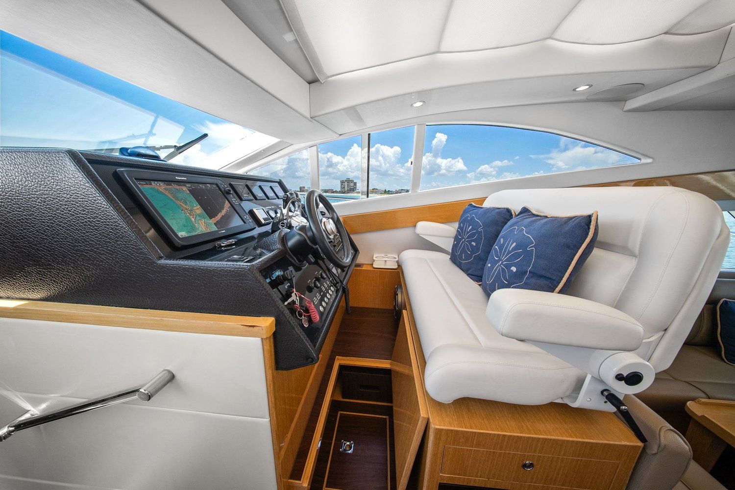 Interior view of a modern catamaran with a sleek helm station and comfortable white seating.
