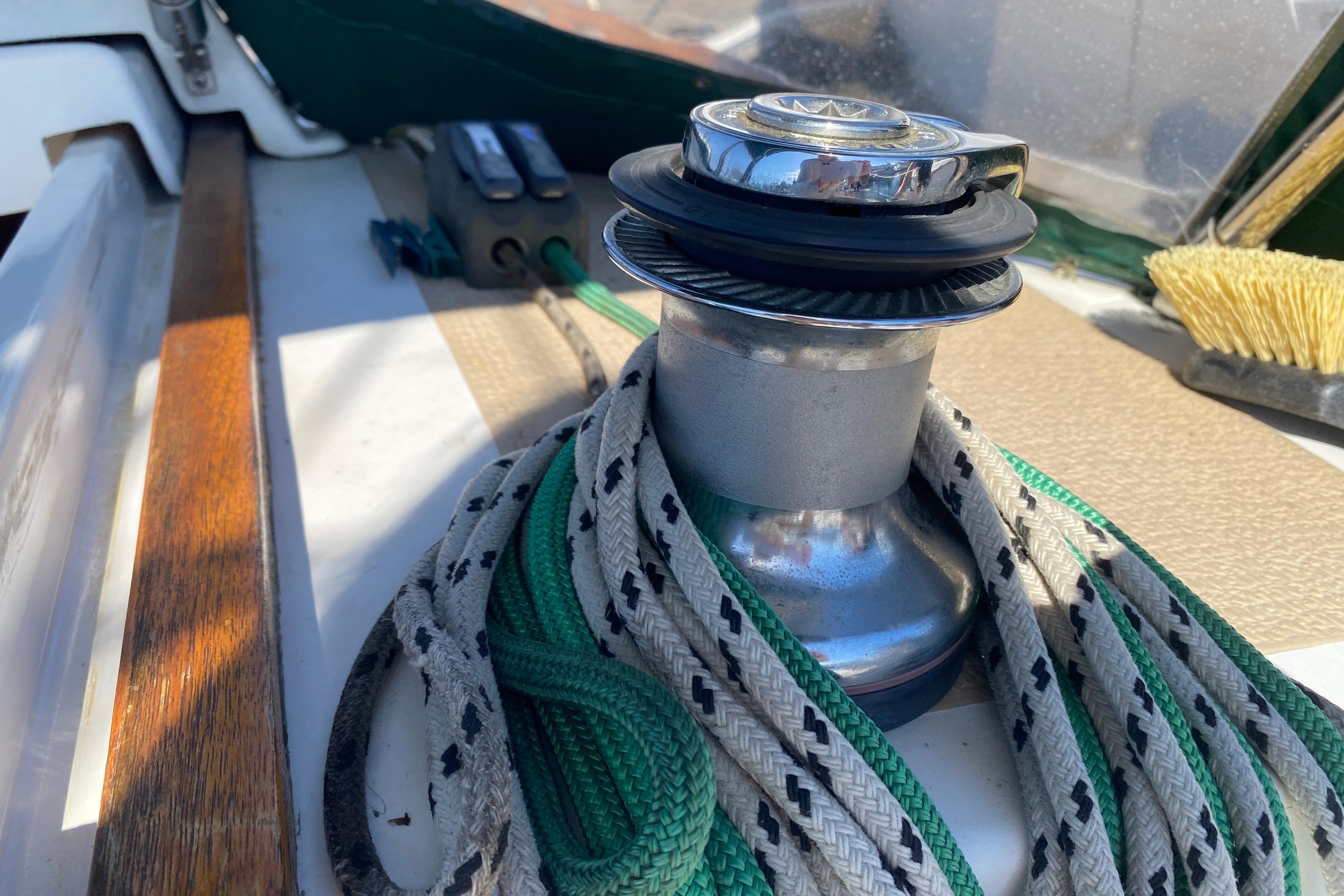 Winch and ropes on 2004 Com-Pac 27 sailboat deck, with brush and controls nearby.
