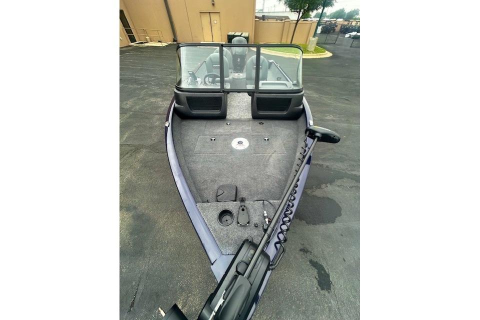 2026 Tracker Pro Guide V-16 WT boat with spacious deck and windshield, parked outdoors.