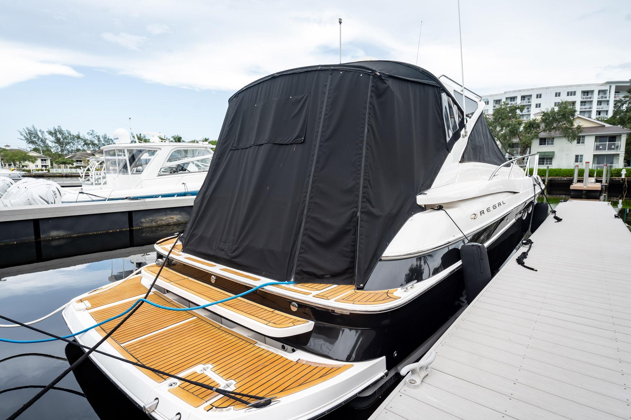 2008 Regal Commodore 4460 yacht docked with black cover, wooden deck, and sleek design.