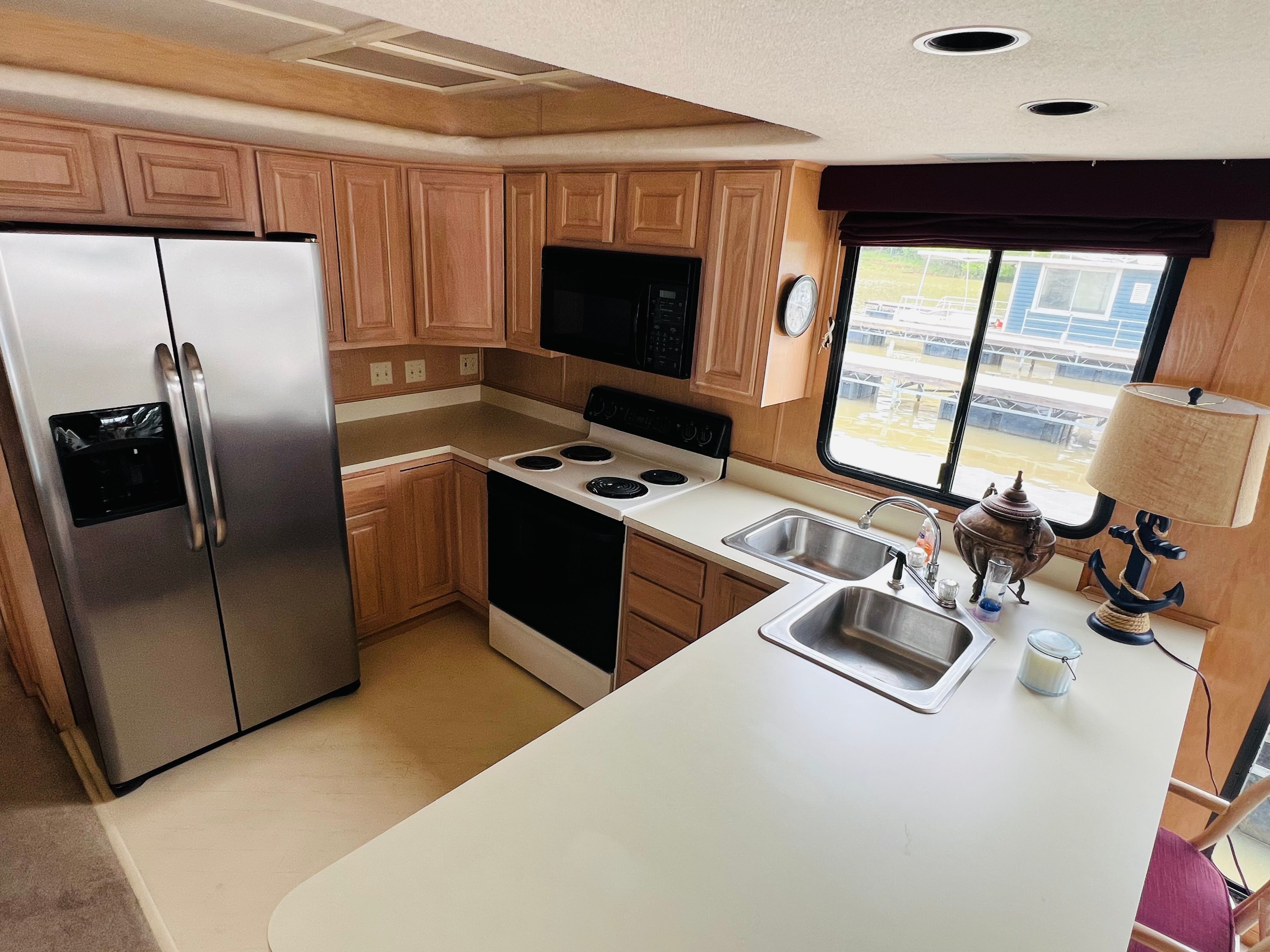 Kitchen interior of a 1998 Sumerset houseboat with modern appliances and wooden cabinetry.