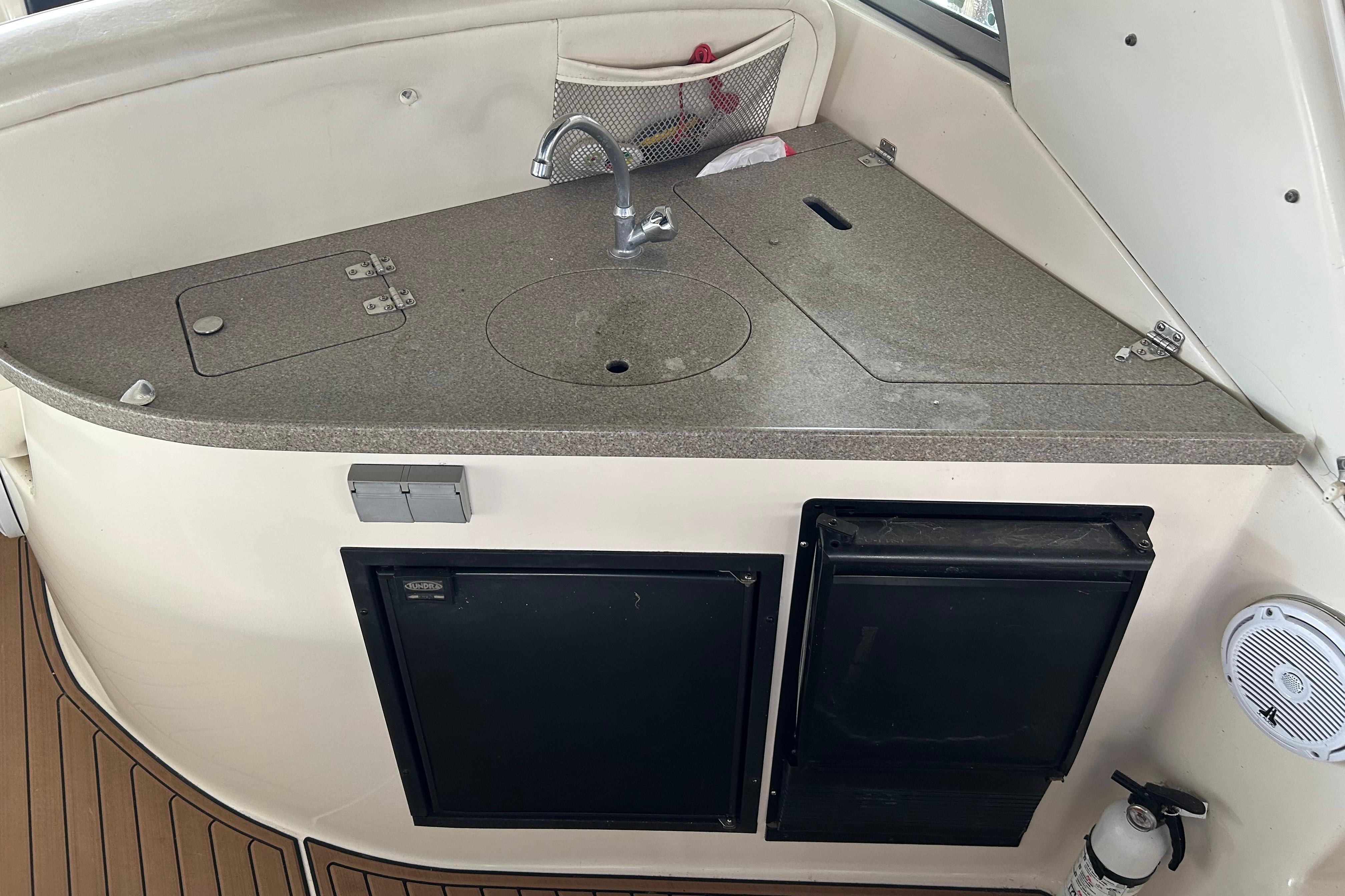 2003 Rinker 342 Express Cruiser kitchenette with sink, storage, and appliances.