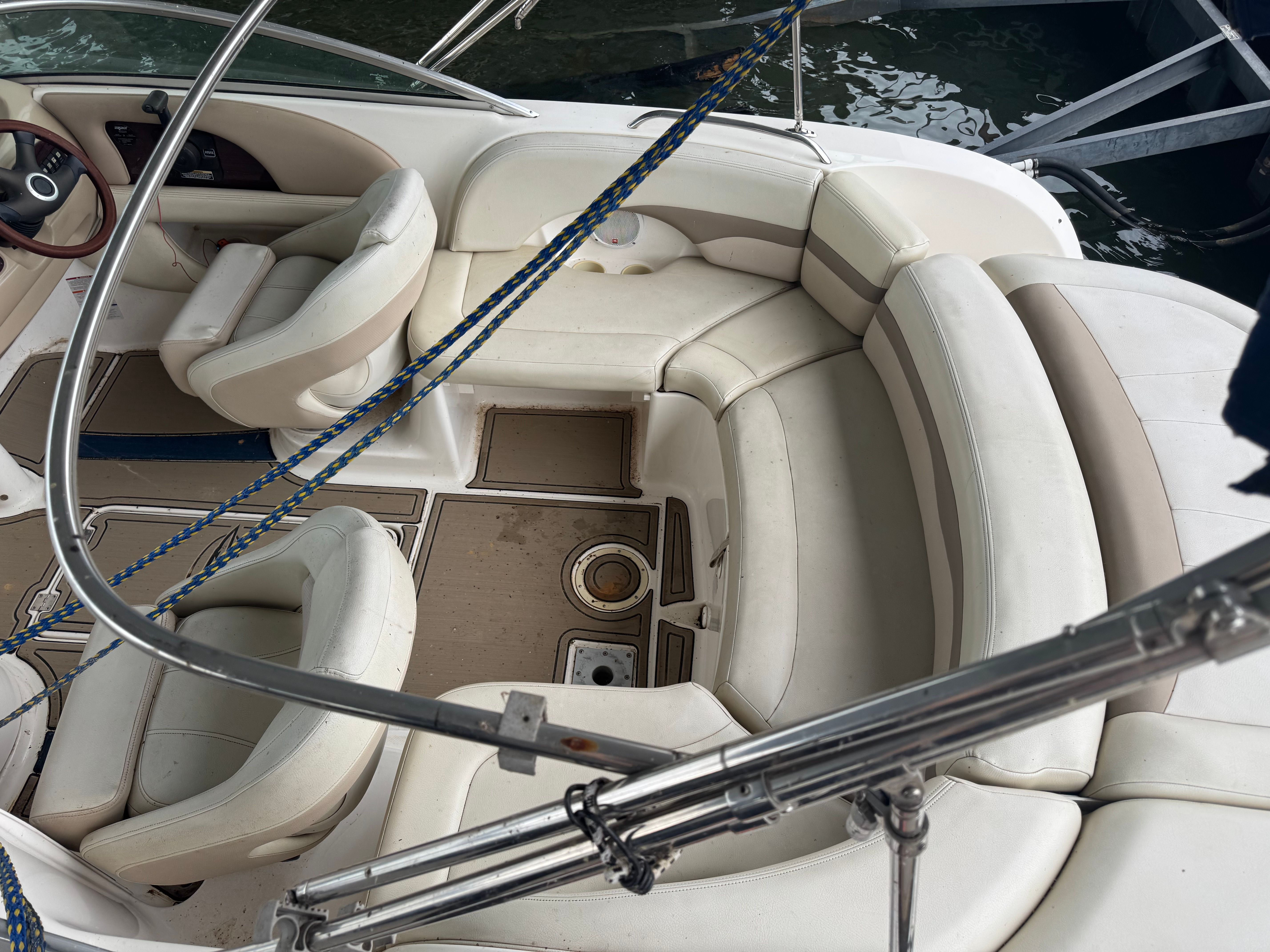 A Chaparral Sunesta 223 boat with white leather seats and blue ropes in a harbor.