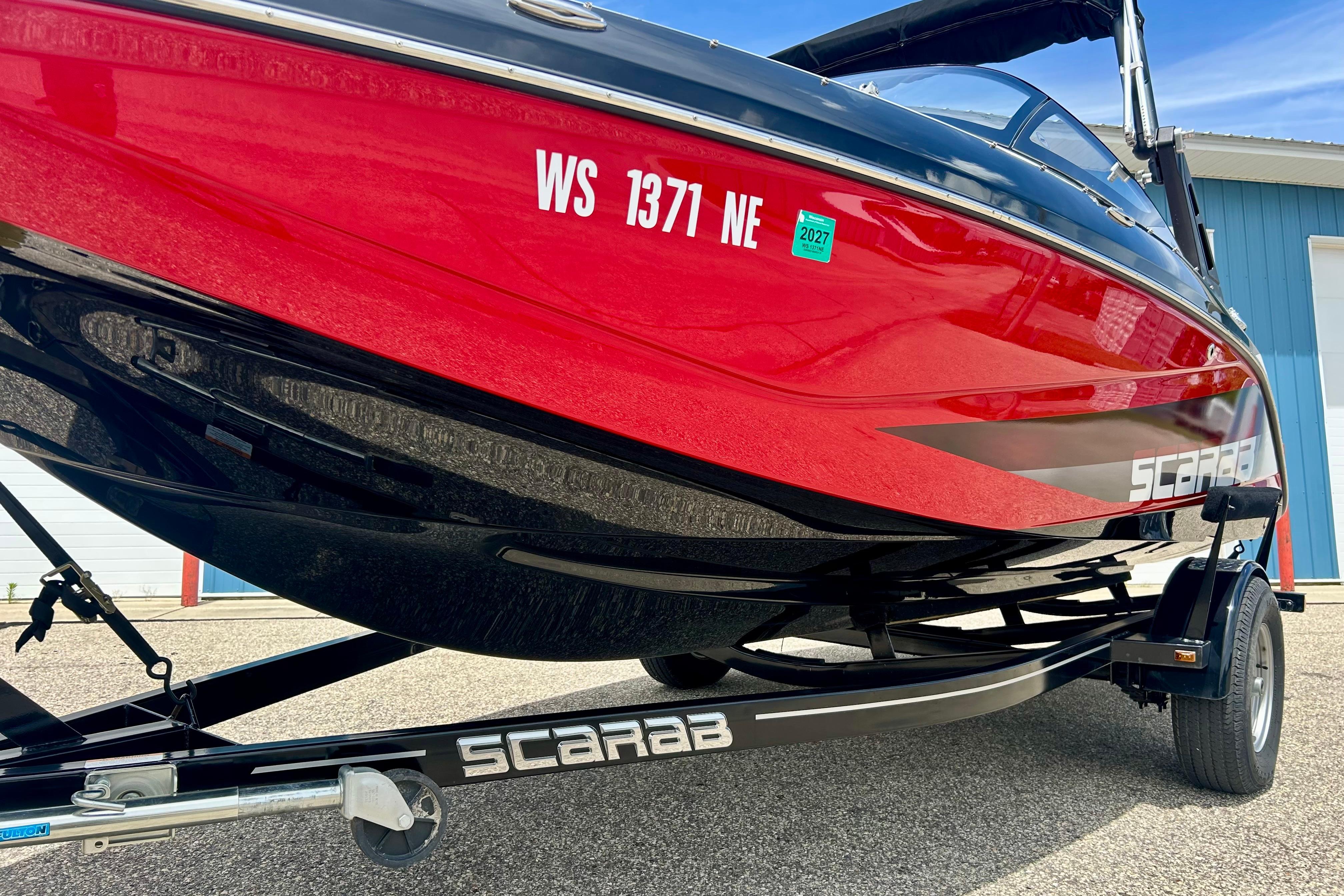 Red 2021 Scarab 195 ID boat on trailer, parked outdoors.