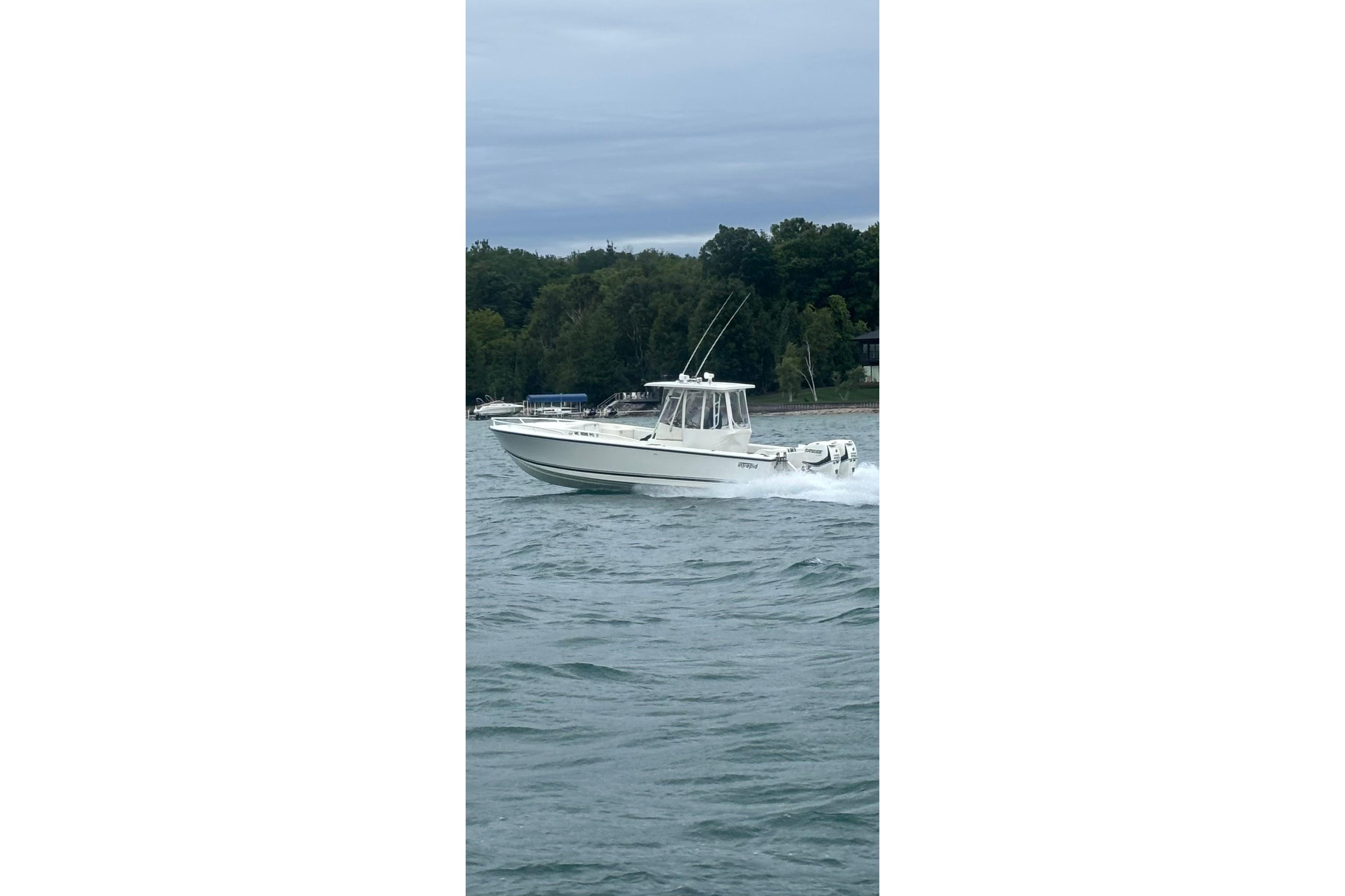 1994 Intrepid 30 Open Cuddy boat cruising on a lake with forested shoreline.