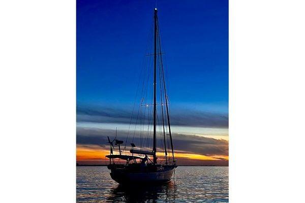 Sailboat silhouette at sunset, Reliance 44 model, 2011, on calm water.