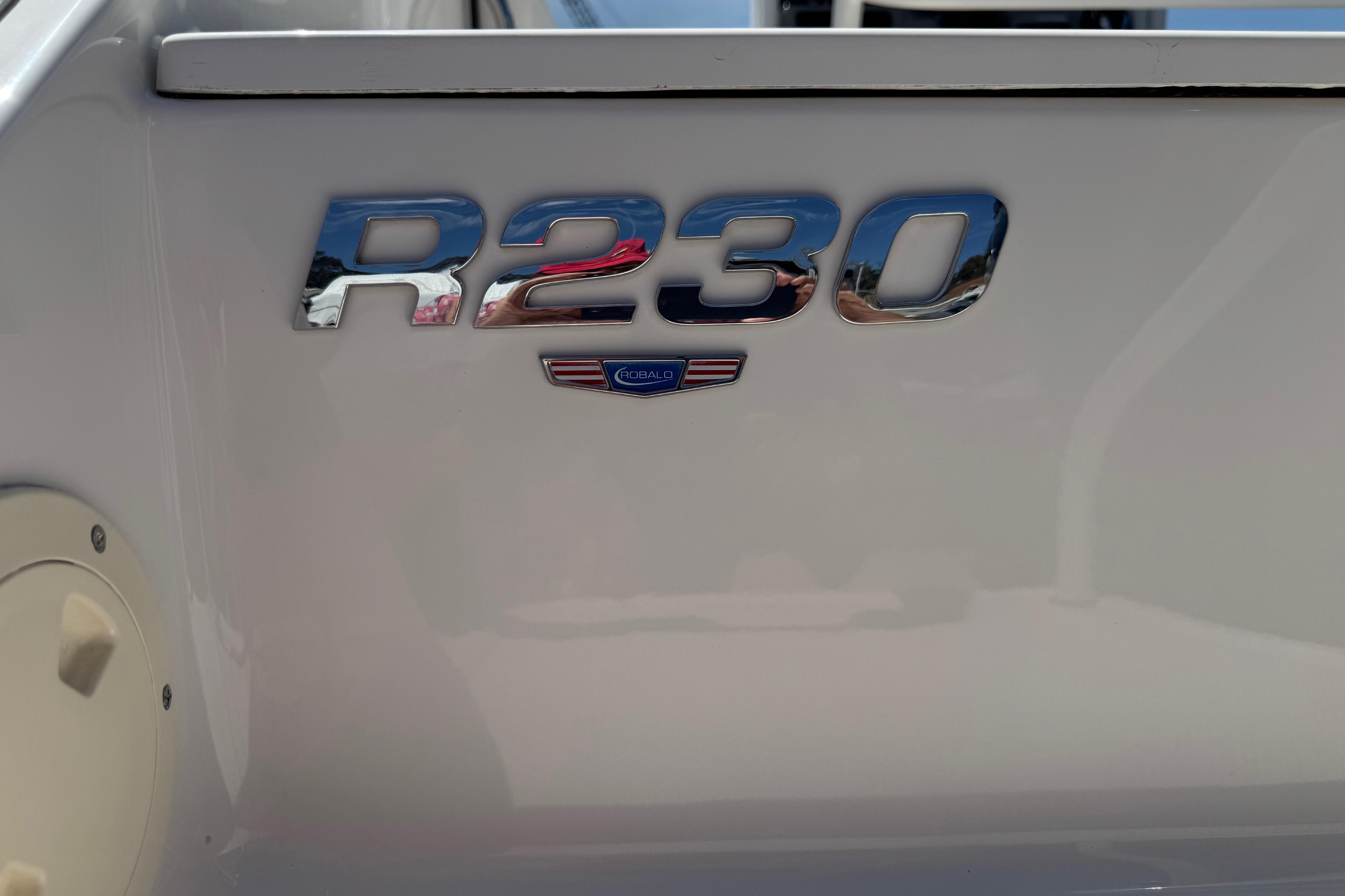 2022 Robalo R230 Center Console boat emblem on a sleek white surface.