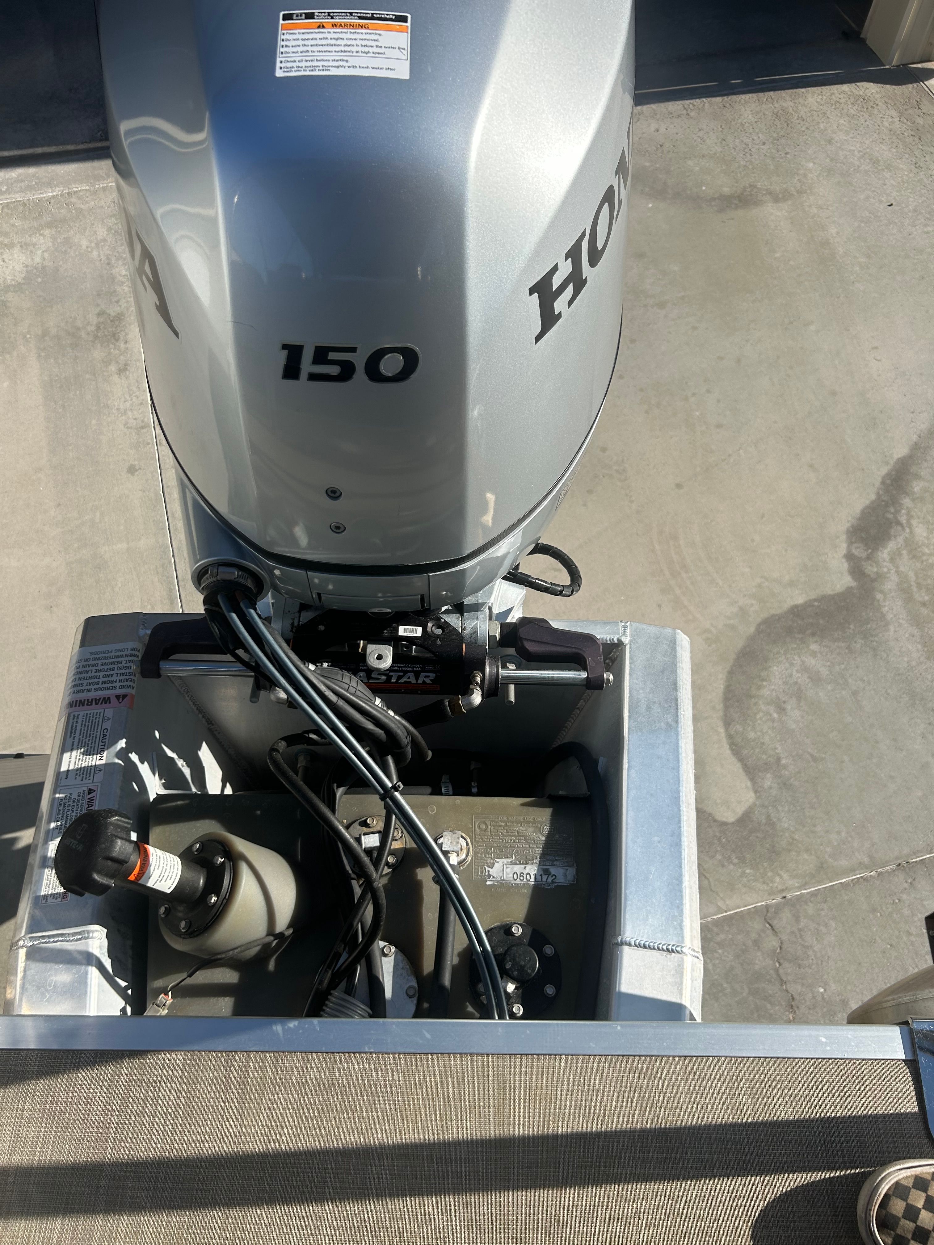 A Honda 150 outboard motor is mounted on a boat. The ground is concrete.
