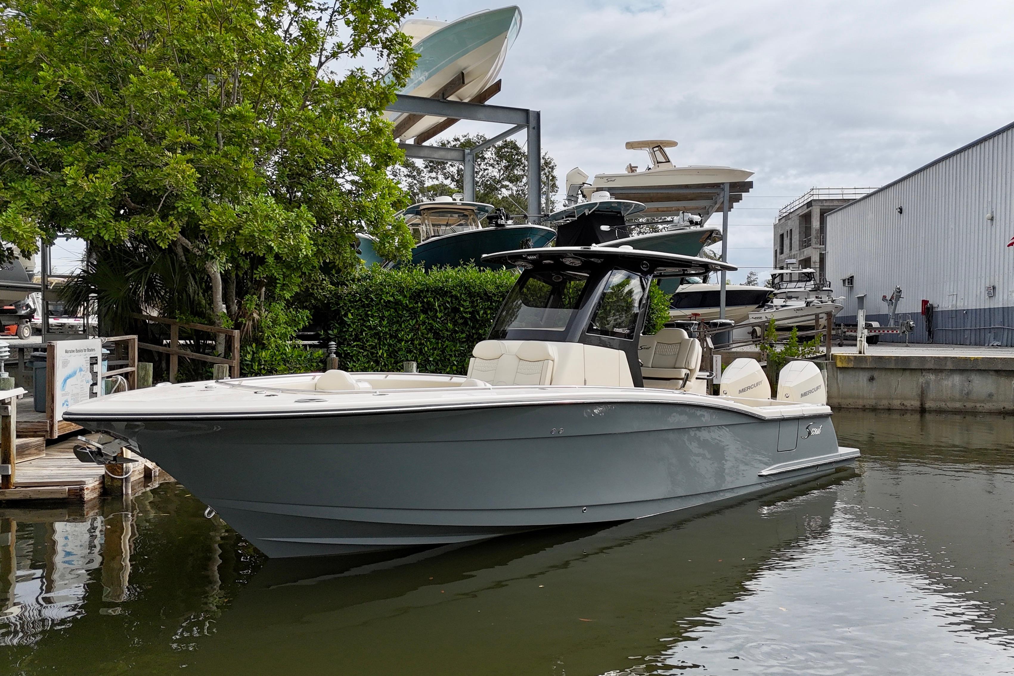 2026 Scout 288 LXF boat docked near marina, surrounded by trees and buildings.