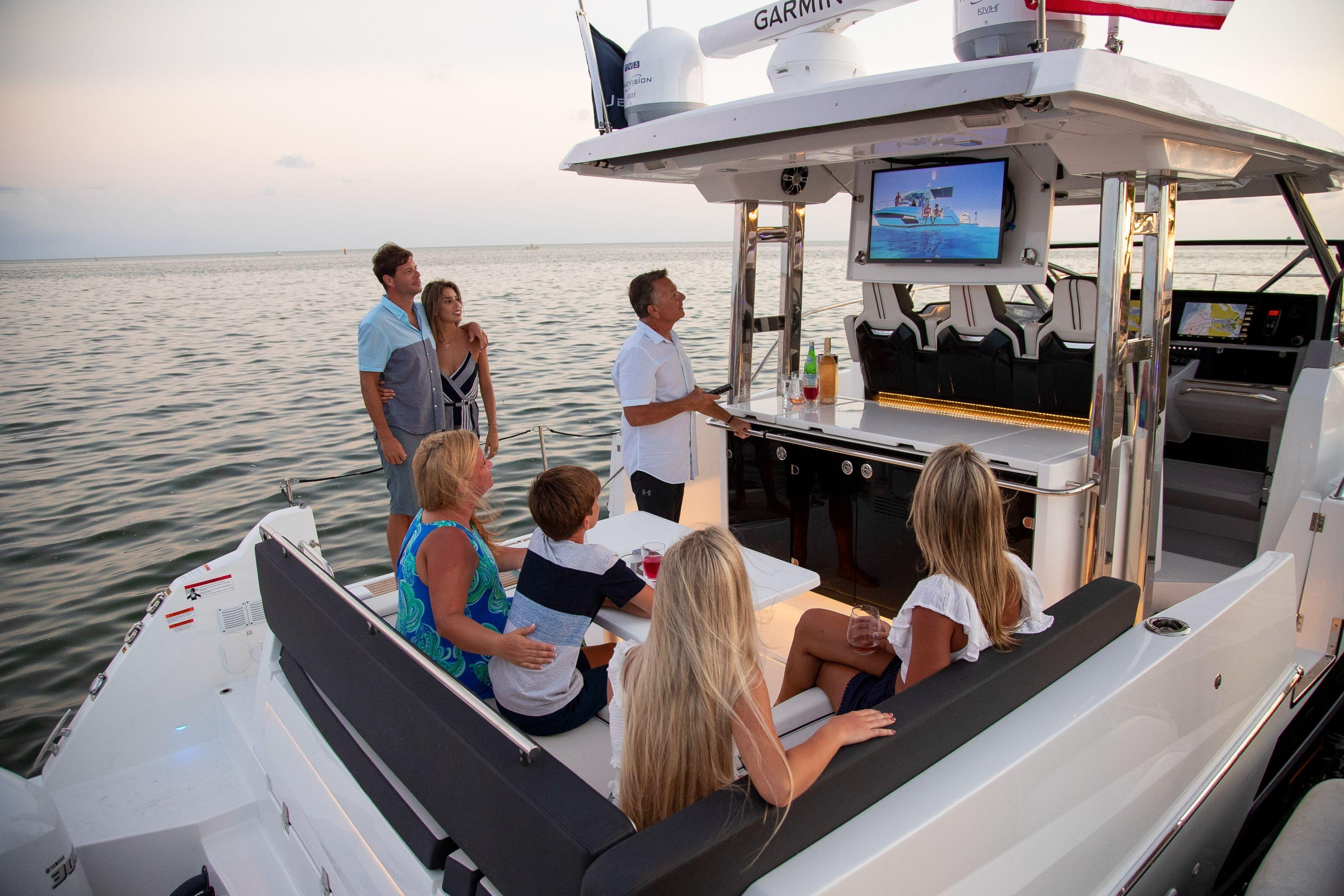Family enjoying sunset on Jeanneau Leader 12.5 WA yacht, 2026 model, with outdoor entertainment.