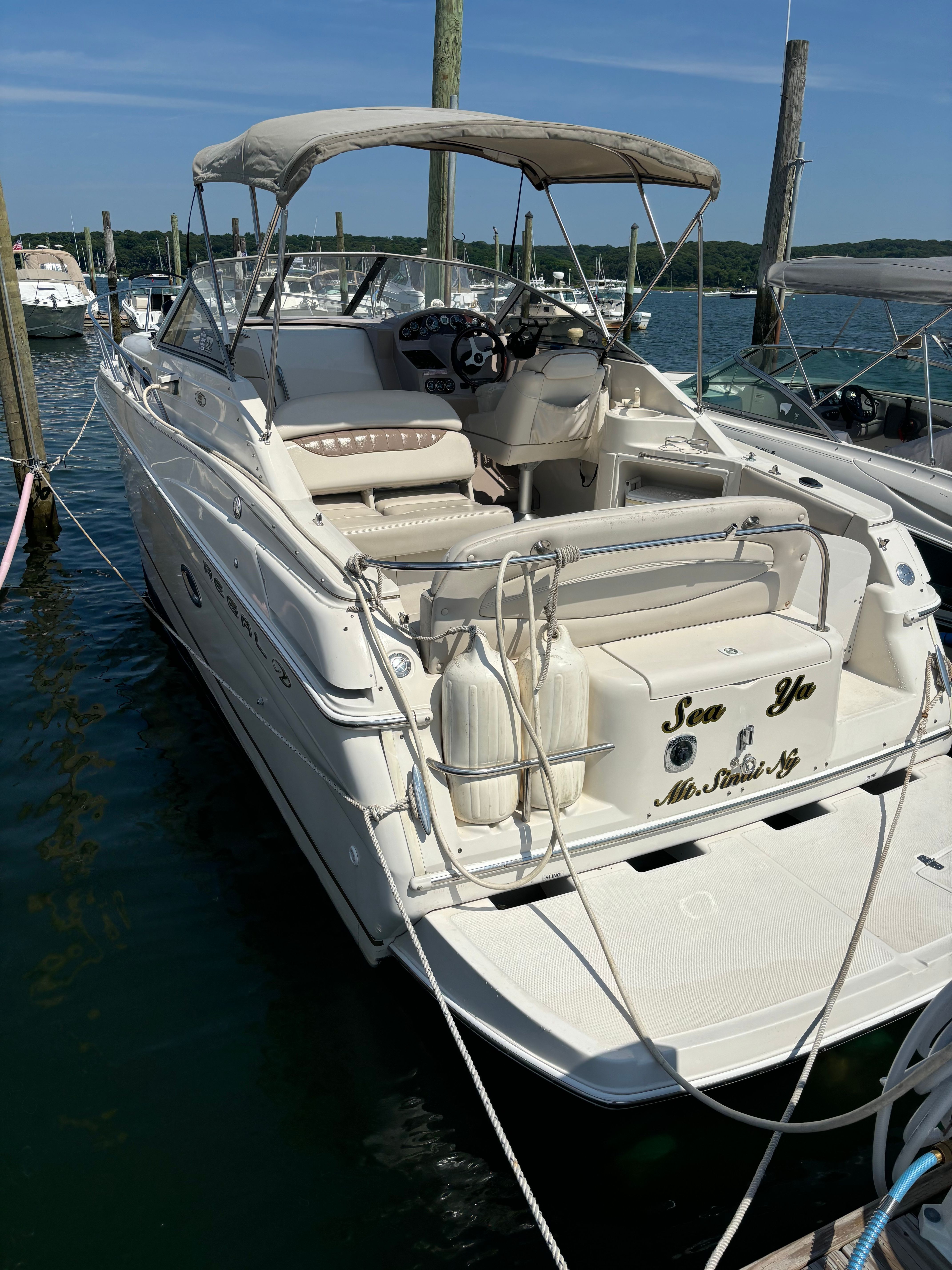 A white motorboat with a canopy is docked in the water.
