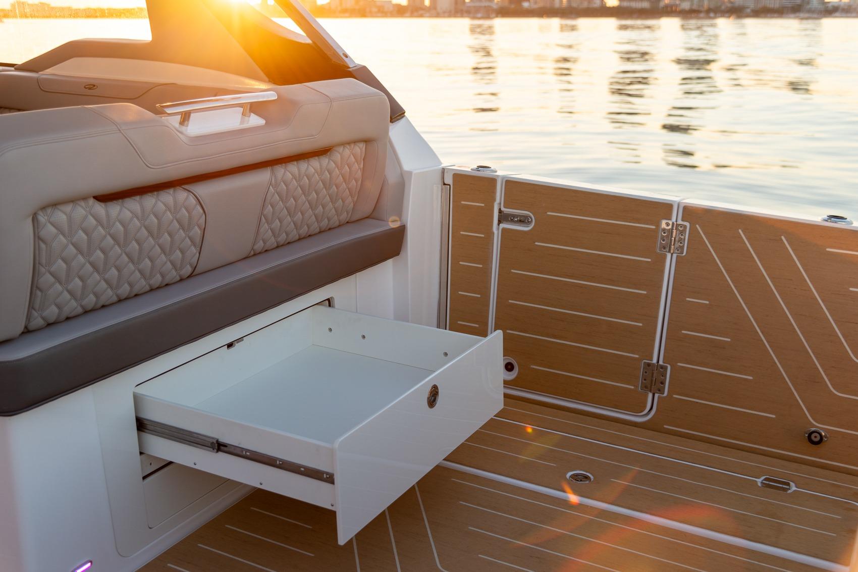 2026 Regal LX43 boat interior with open storage drawer, sunset reflecting on water.