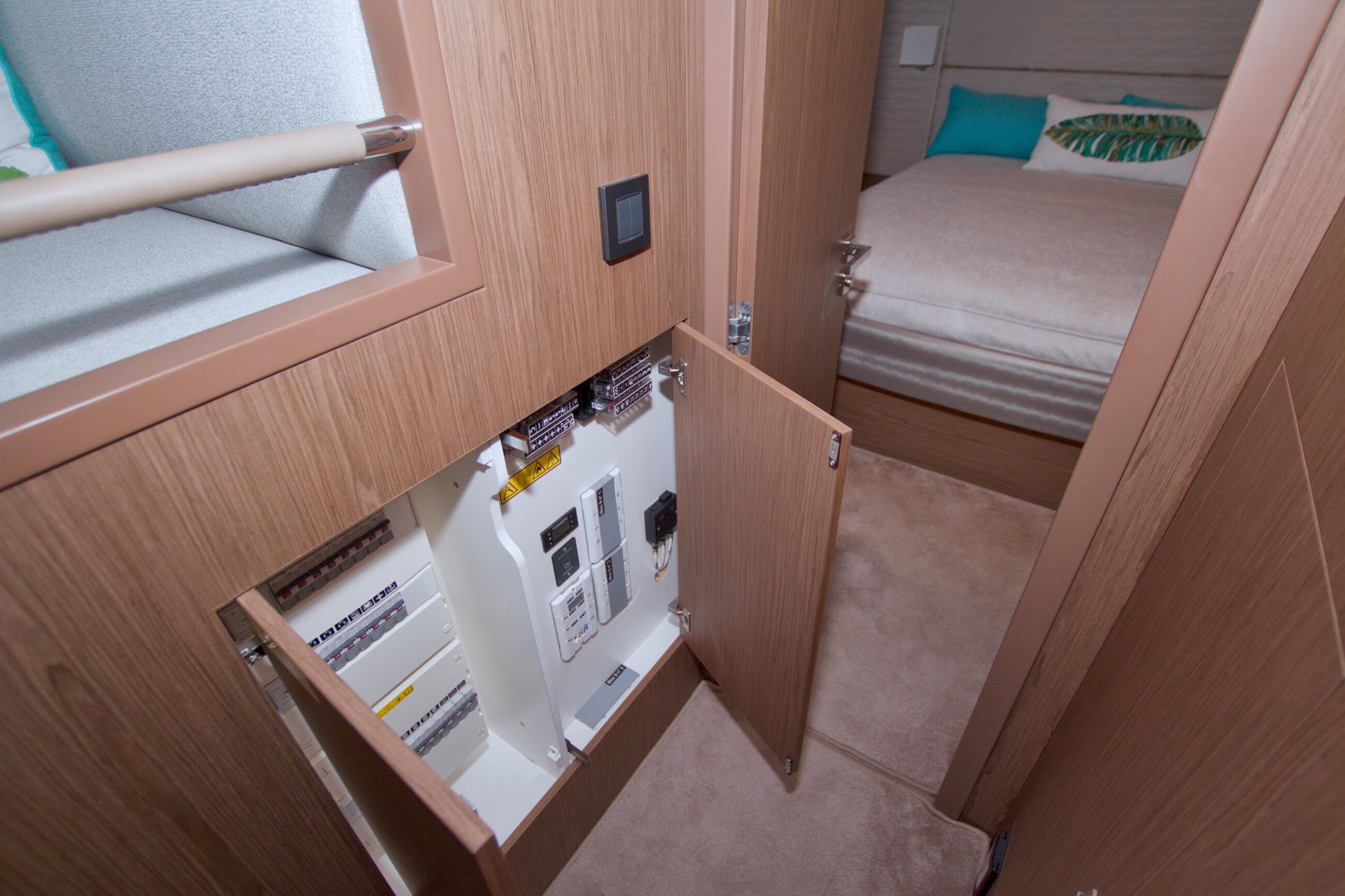 2019 Beneteau Gran Turismo 50 interior with open electrical panel and cozy bedroom.