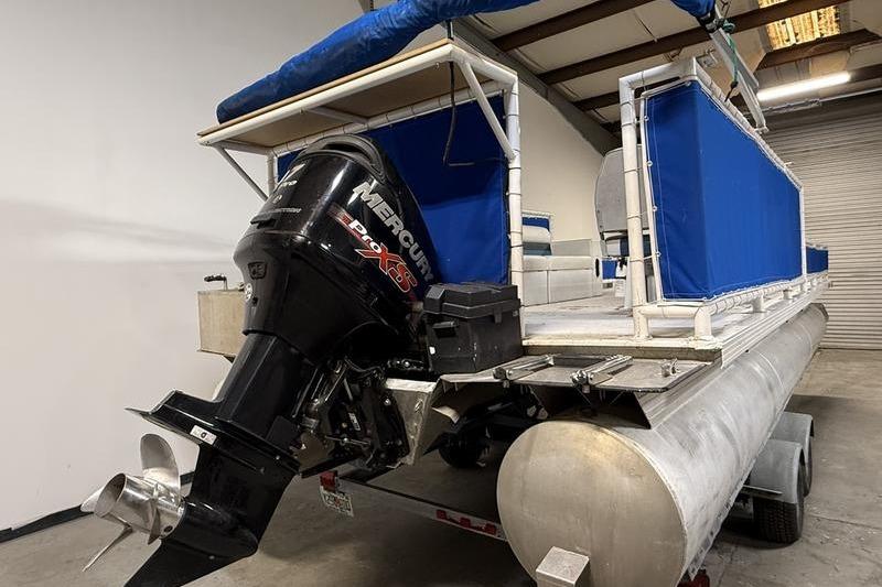 1993 Monark Sun Caster 240 CR 4 Point pontoon boat with Mercury outboard motor in a garage.