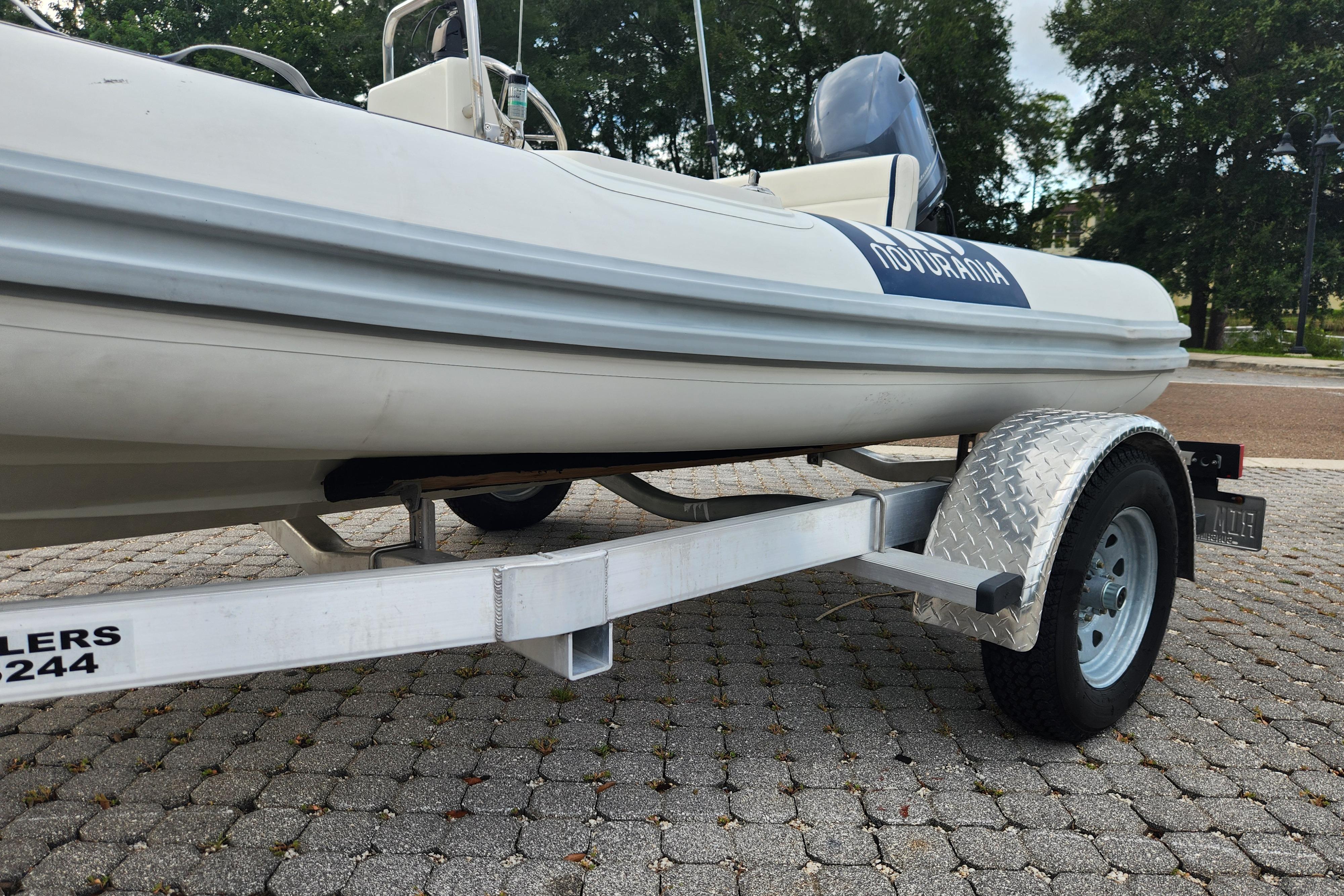 2019 Novurania DL 400 boat on trailer, parked on cobblestone pavement.
