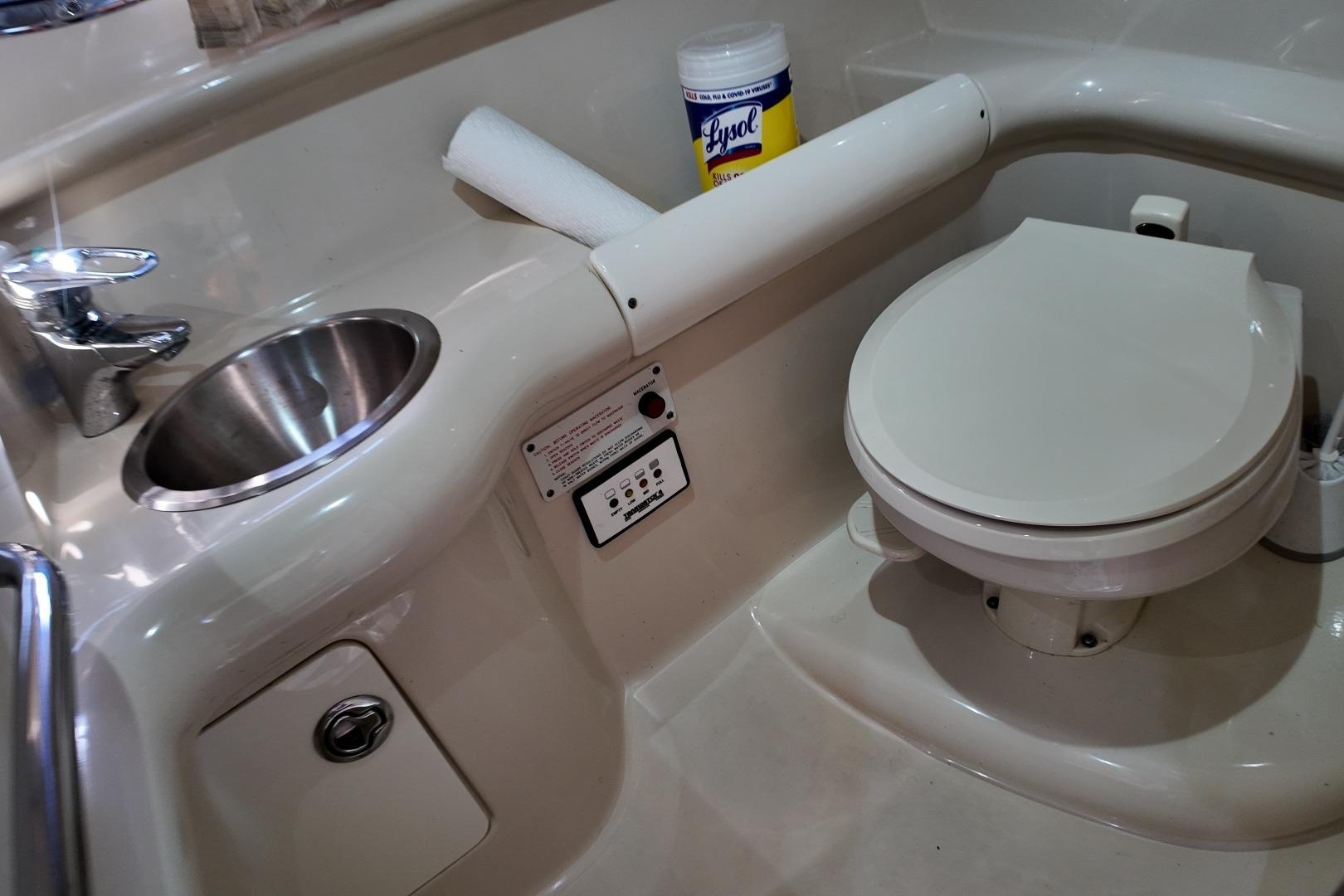 2007 Formula 330 Sun Sport boat bathroom with sink, toilet, and cleaning supplies.