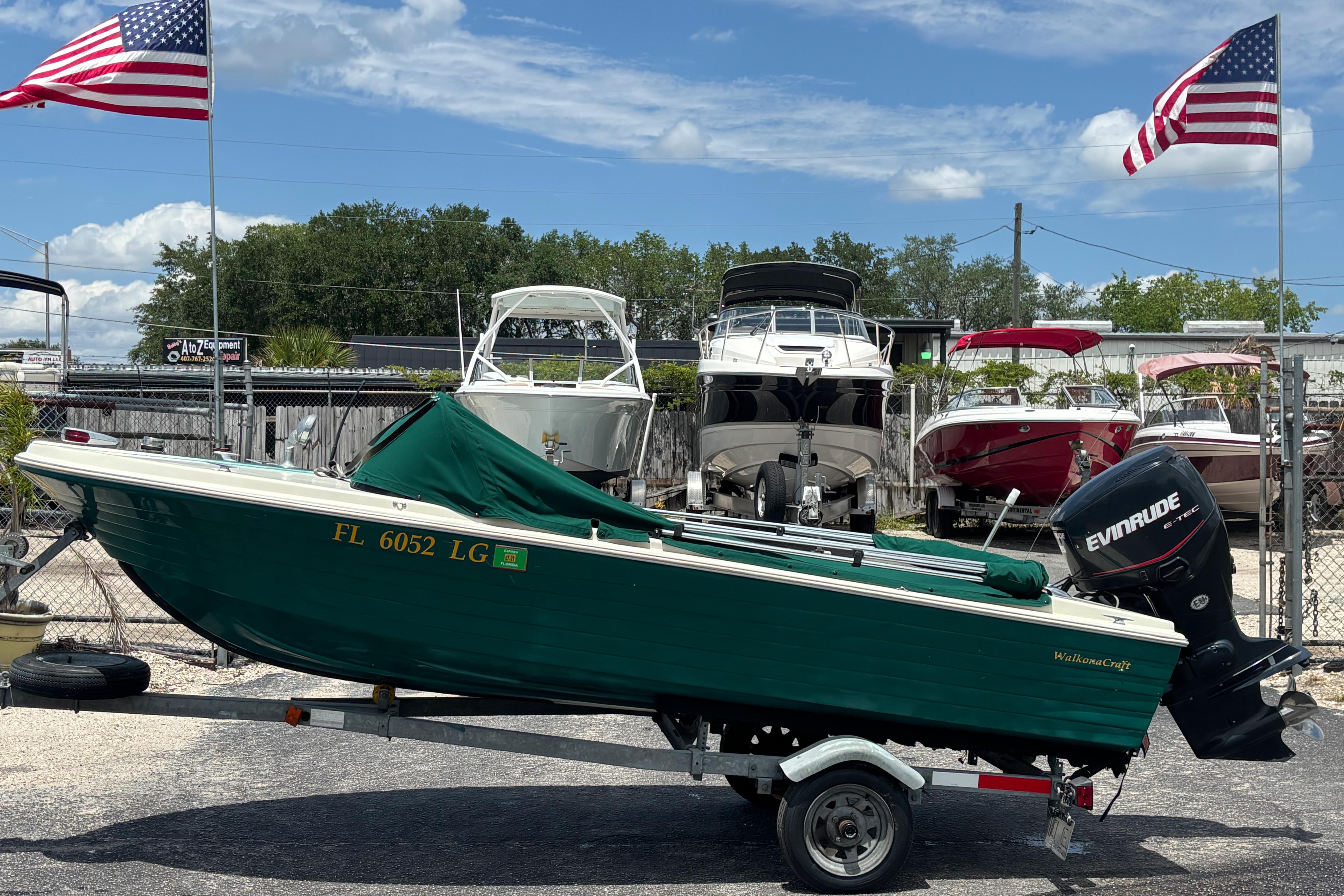 1966 Mohawk 15 boat on trailer, green hull, Evinrude motor, American flags in background.