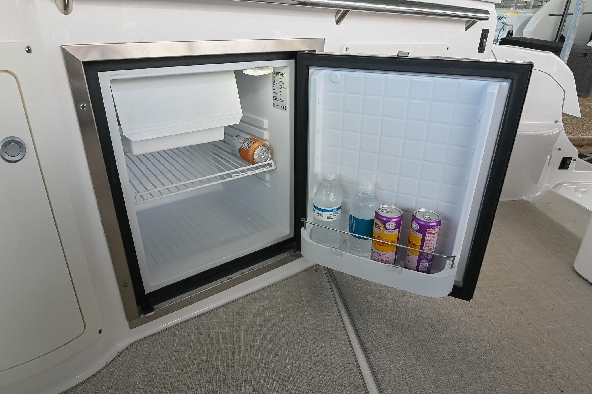 Mini fridge on 2021 Regal 33 Express boat, stocked with drinks and ice compartment.