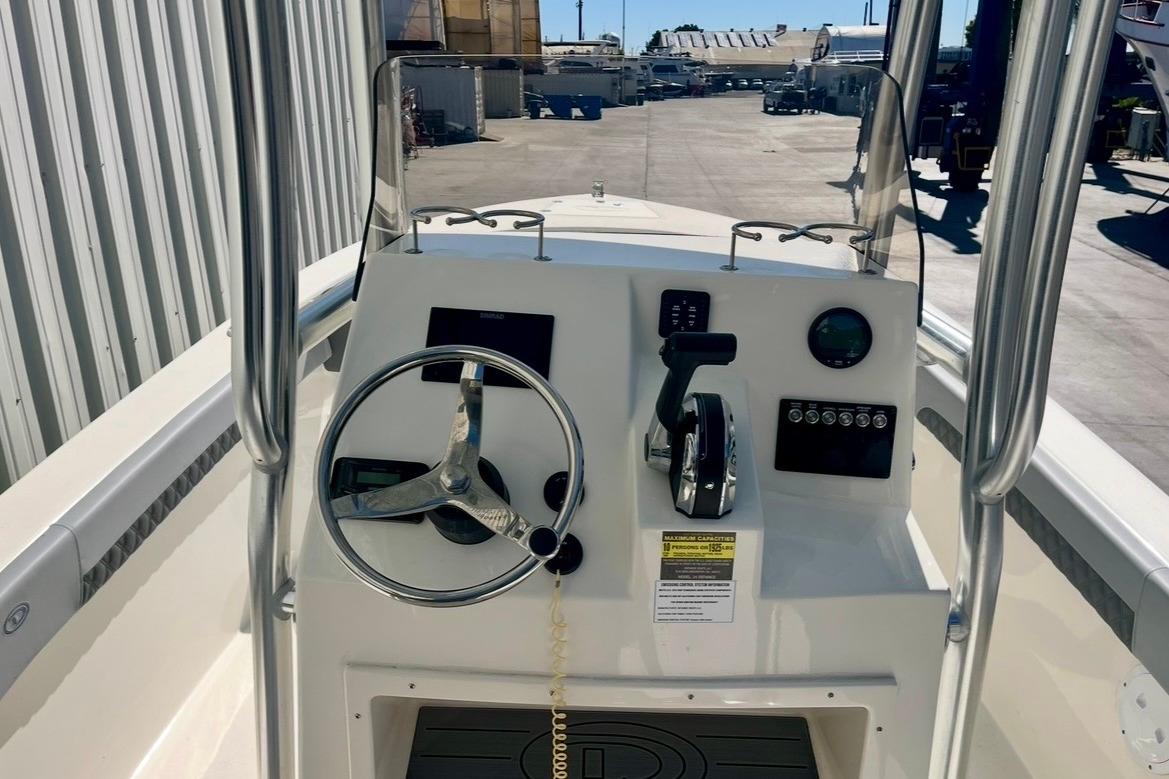 Control panel of 2025 Defiance Catalina 240 boat, featuring steering wheel and throttle.