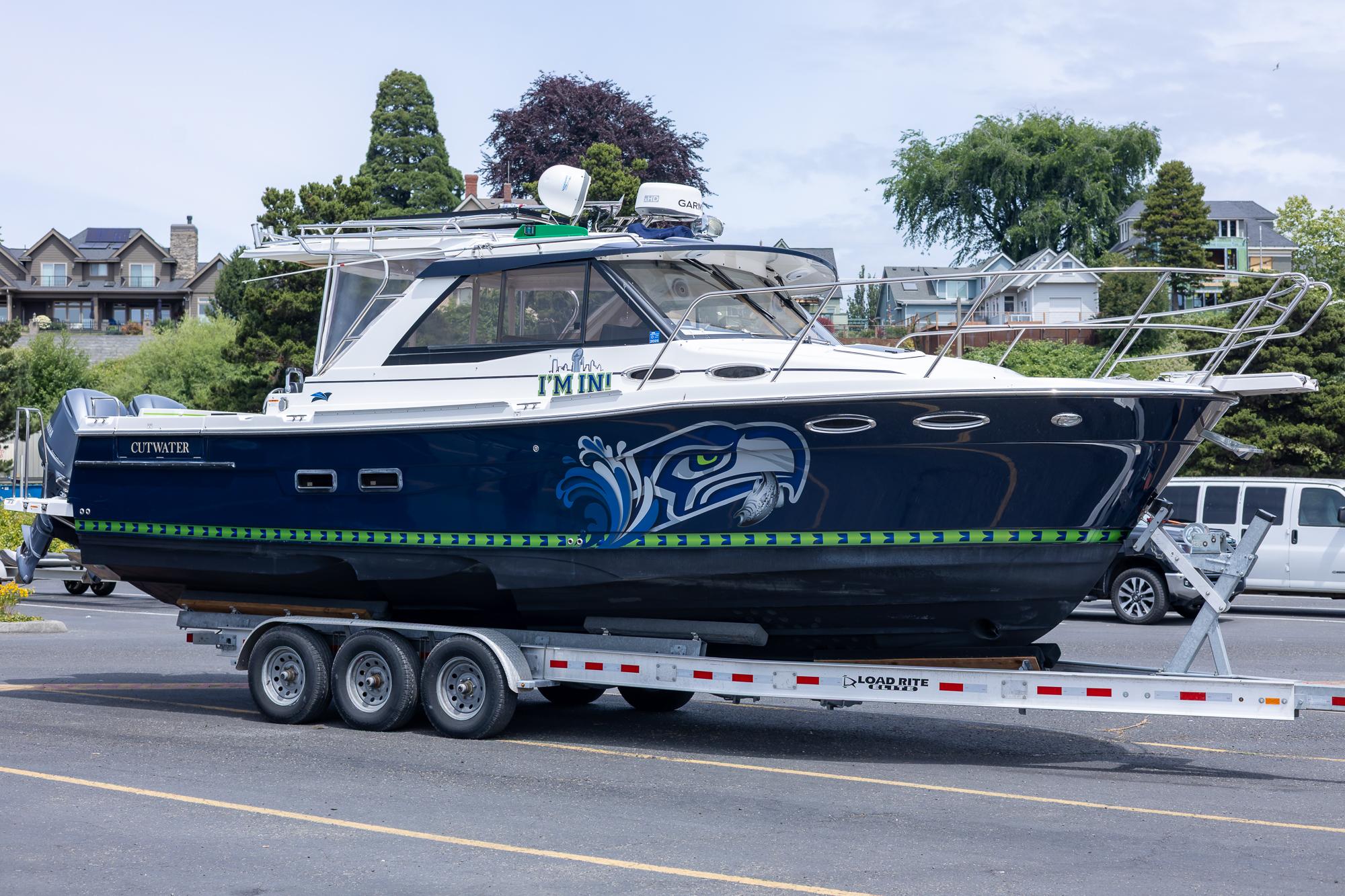 2017 Cutwater C-302 Sport Coupe boat on trailer, featuring custom graphics and parked in a residential area.