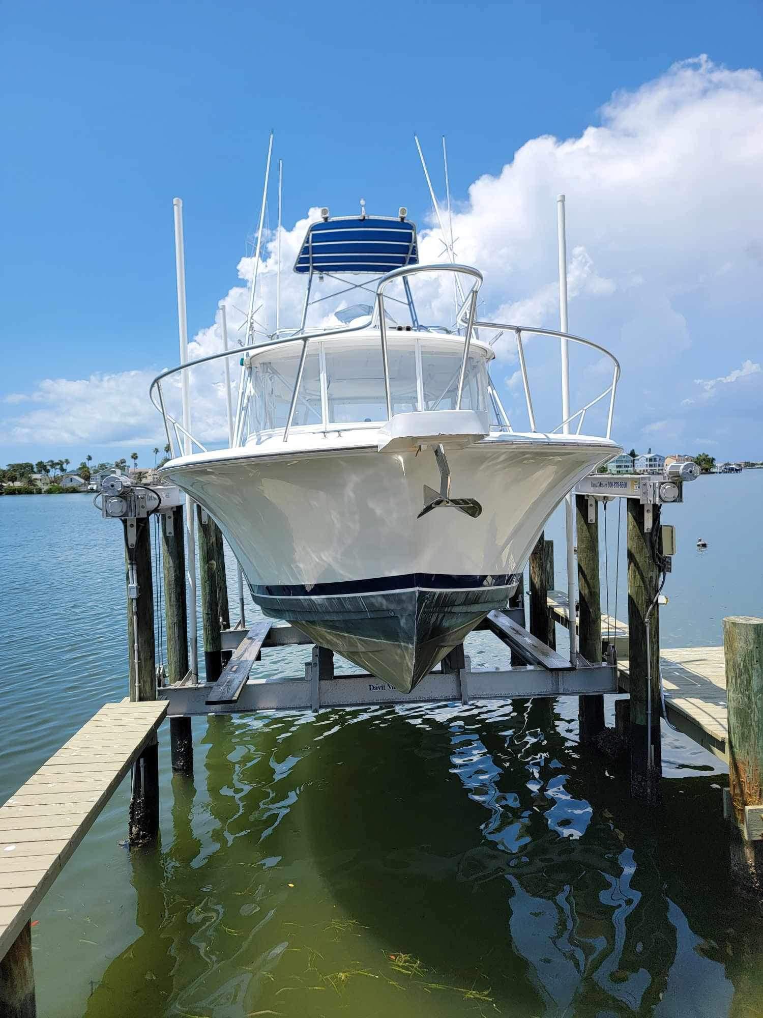 1997 Luhrs 32 Open boat on lift, docked by calm waters under a clear sky.