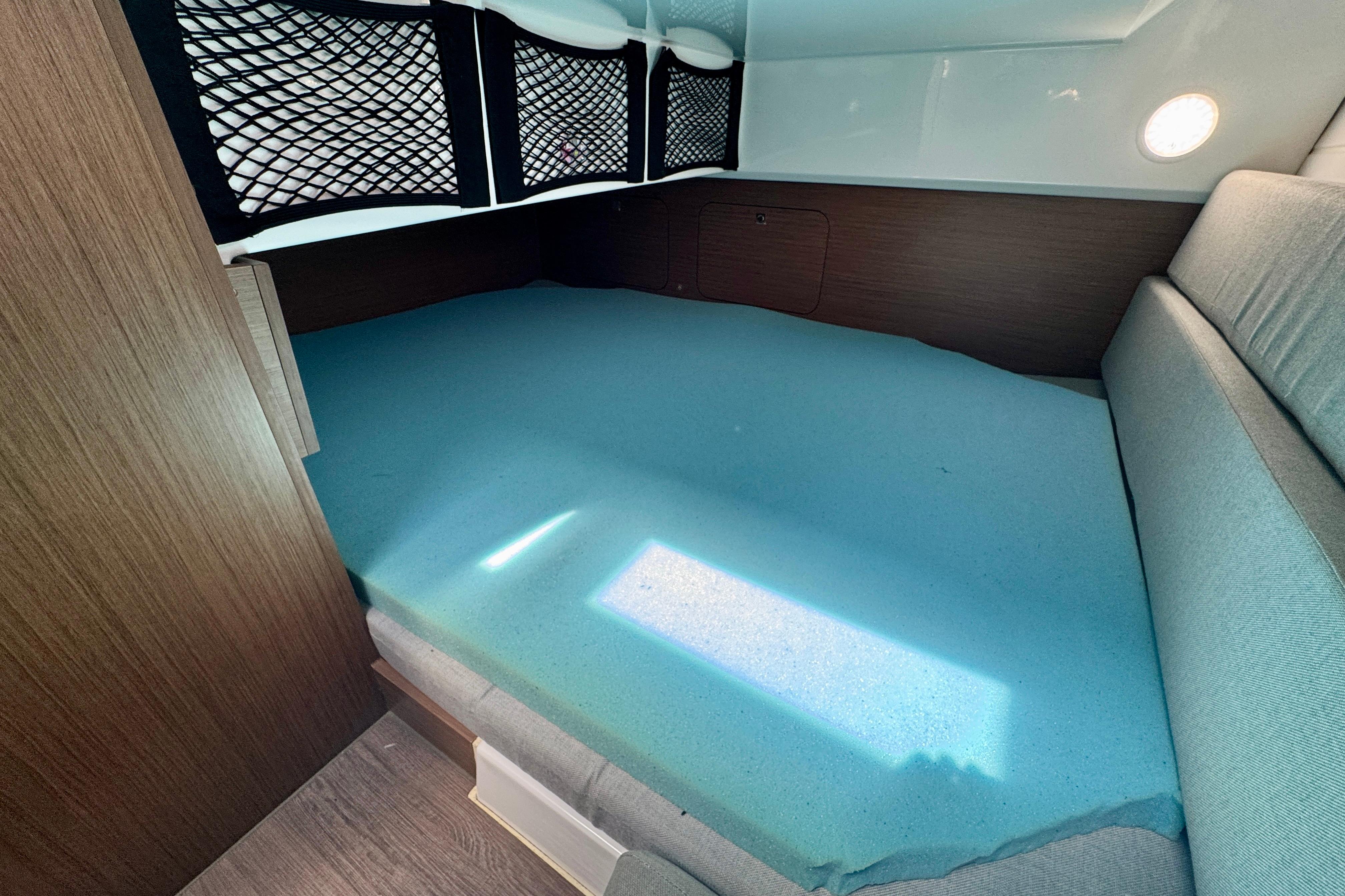 2020 Jeanneau NC 895 cabin interior with blue mattress and wooden accents.