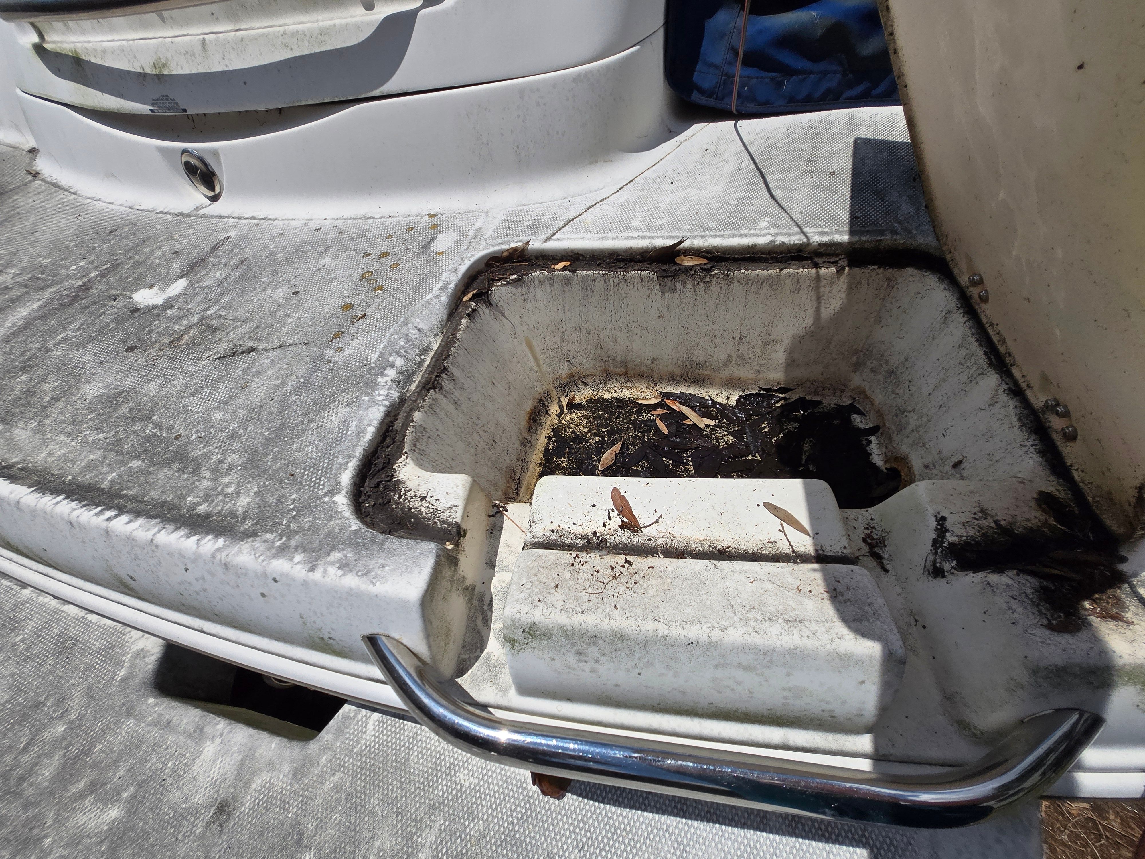 A worn area on a boat with dirt and leaves.