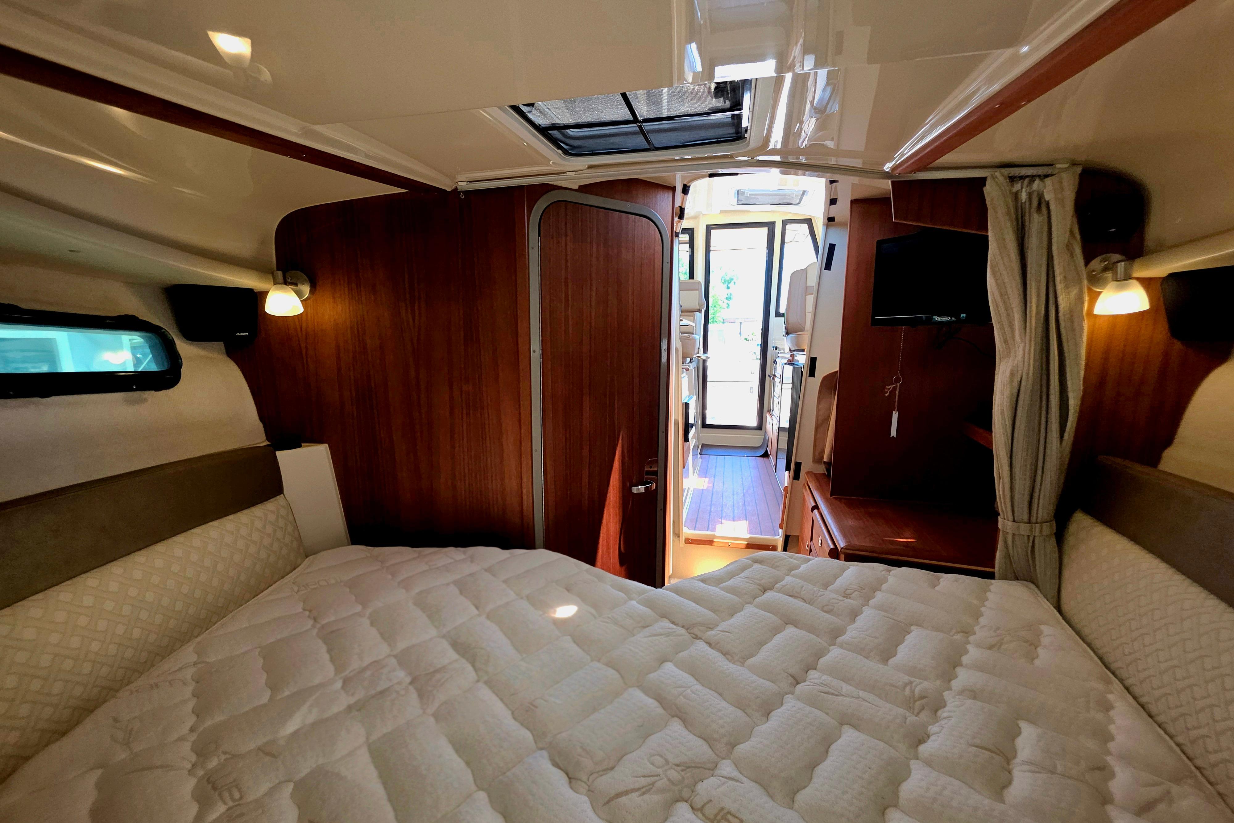Cozy cabin interior of 2021 Ranger Tug R27 with bed, wood paneling, and natural light.