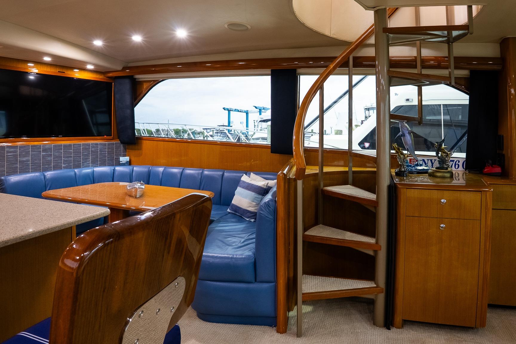Luxurious interior of 2002 Viking 61 Enclosed Bridge yacht with spiral staircase and seating area.