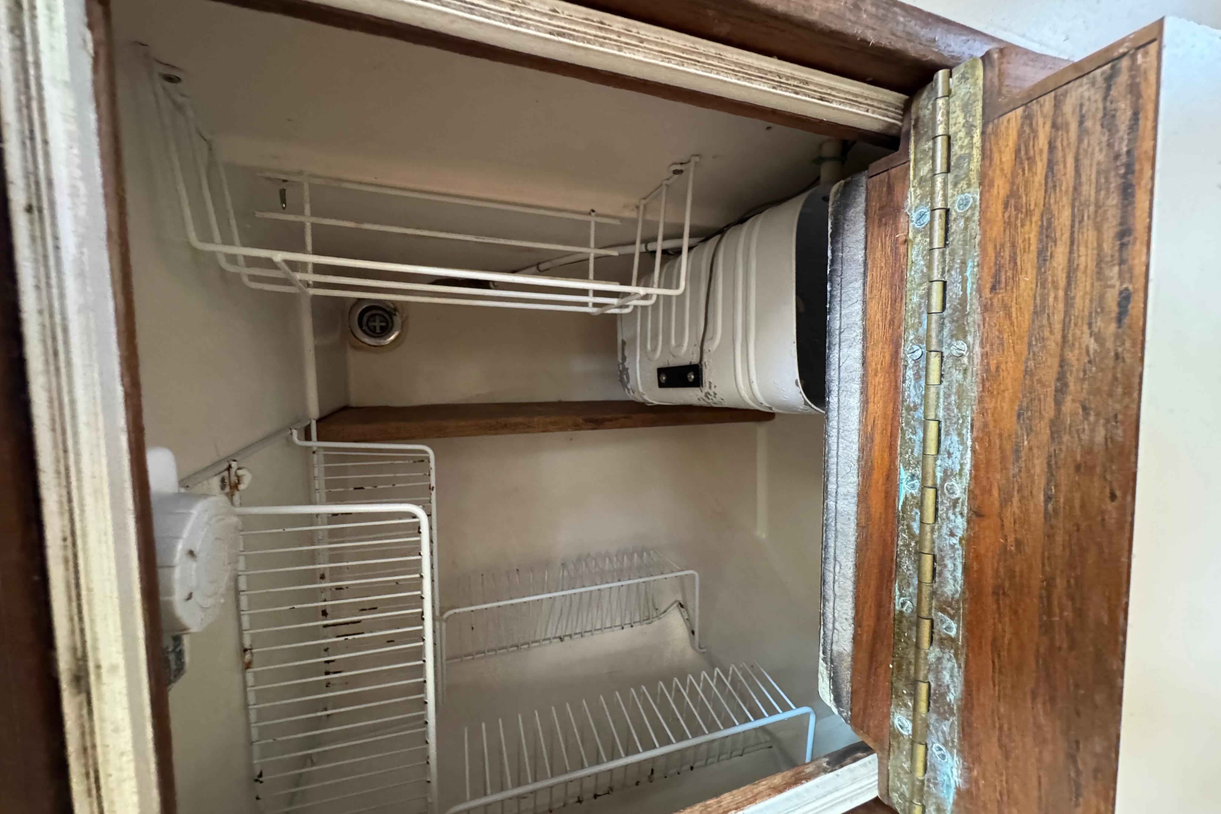 Interior view of a 1989 Cape Dory 30 Motorsailer refrigerator with wire shelving.