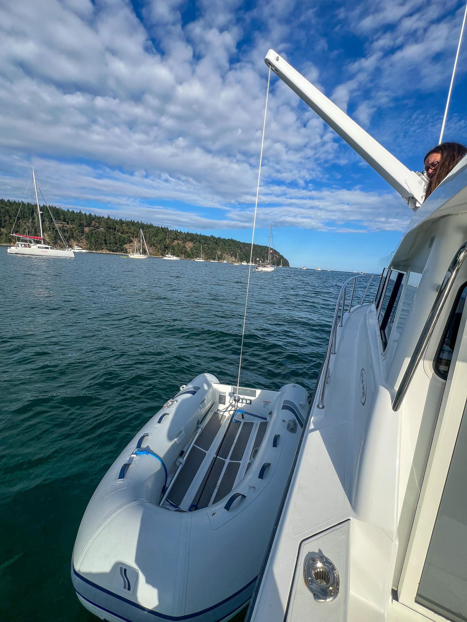 Ocean Sport 26/27 boat with dinghy on calm water, 2021 model, scenic coastal view.