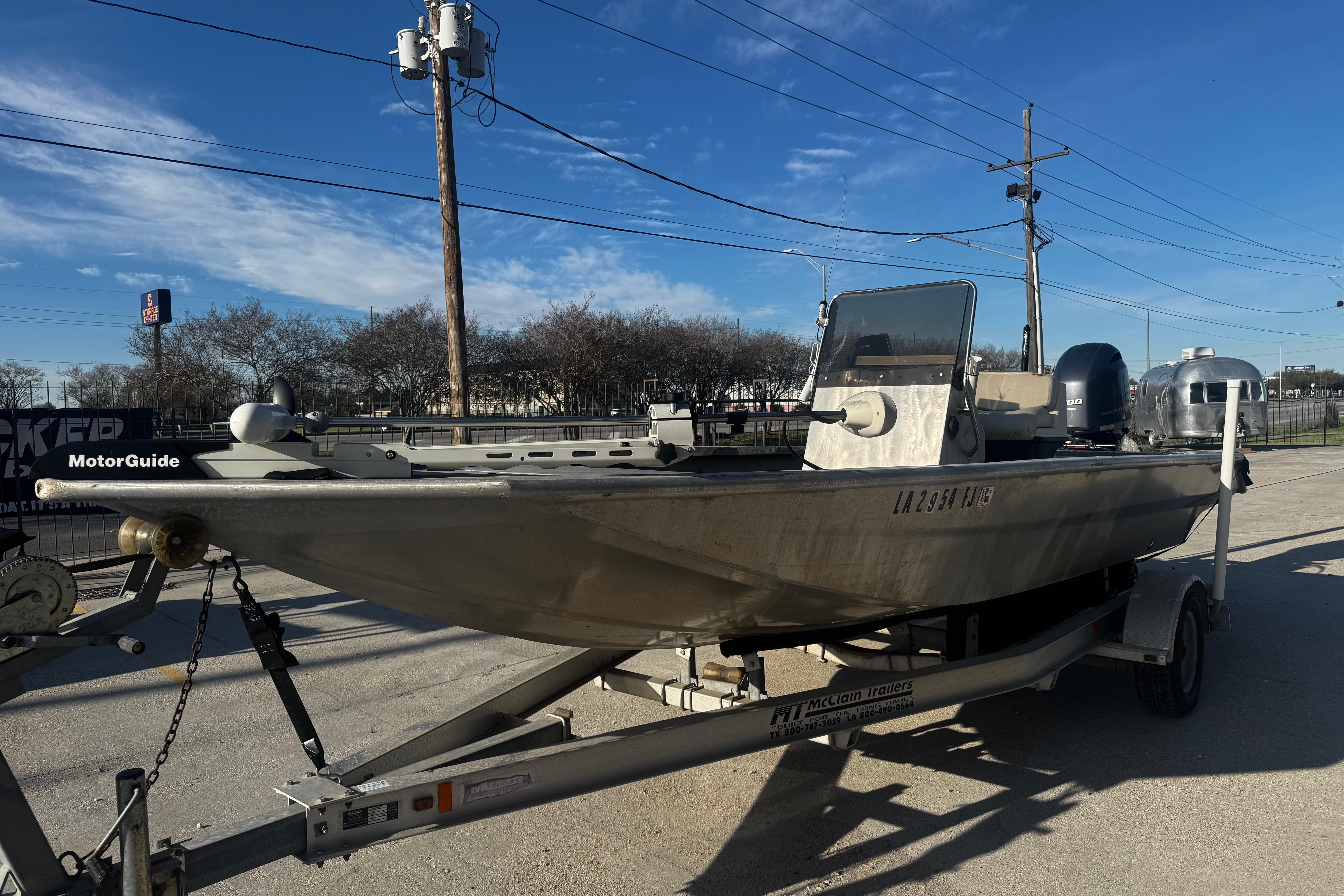 Custom Charles Leonard 21 boat on trailer, 2004 model, parked outdoors under clear blue sky.