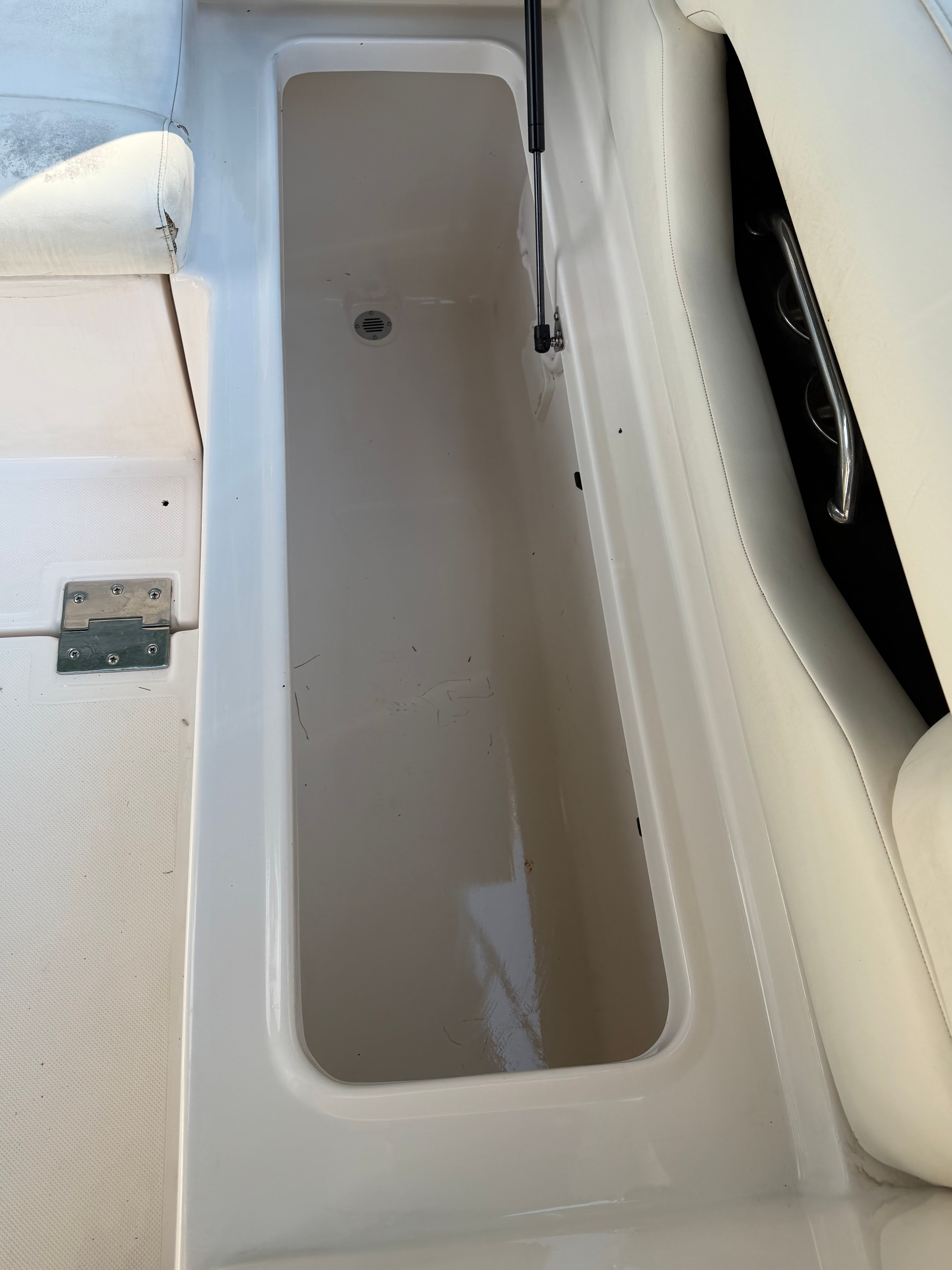 An open storage compartment on a 2011 Regal 2750 Cuddy boat, featuring a gas strut.
