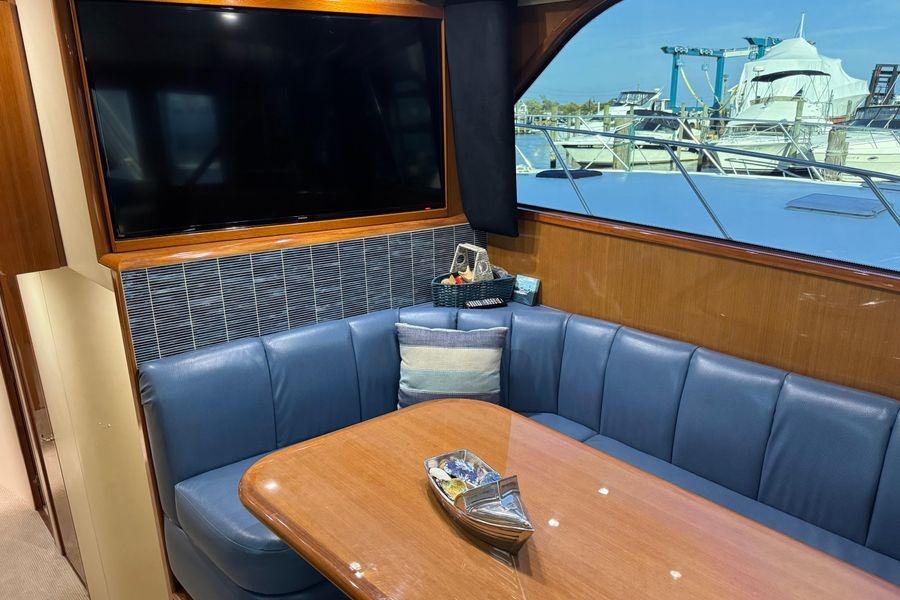 Luxurious interior of 2002 Viking 61 Enclosed Bridge yacht with blue seating and large TV.