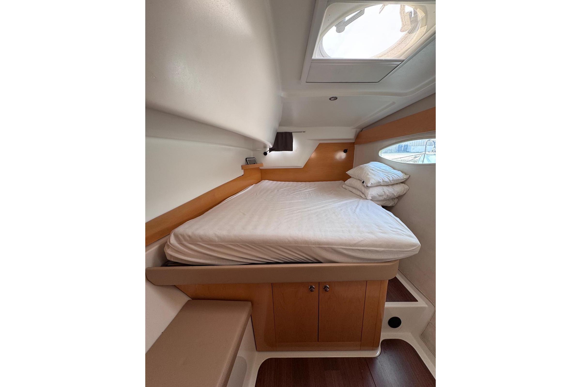 Cozy cabin interior of 2009 Fountaine Pajot Orana 44 catamaran with bed and porthole.