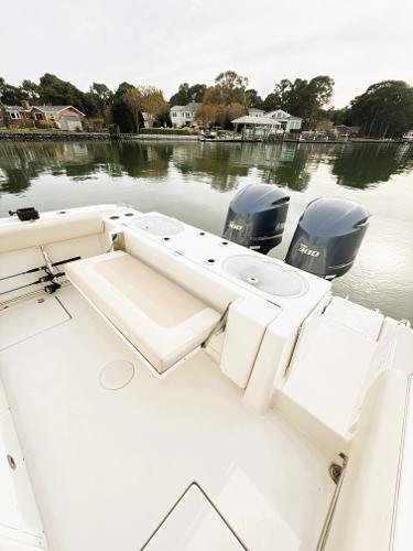 2016 Cobia 296 Center Console boat with dual engines docked by a serene waterfront.