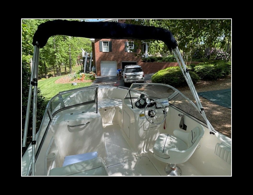 2004 Sea Hunt Escape with open cockpit and helm, in a garden setting in front of a brick house.