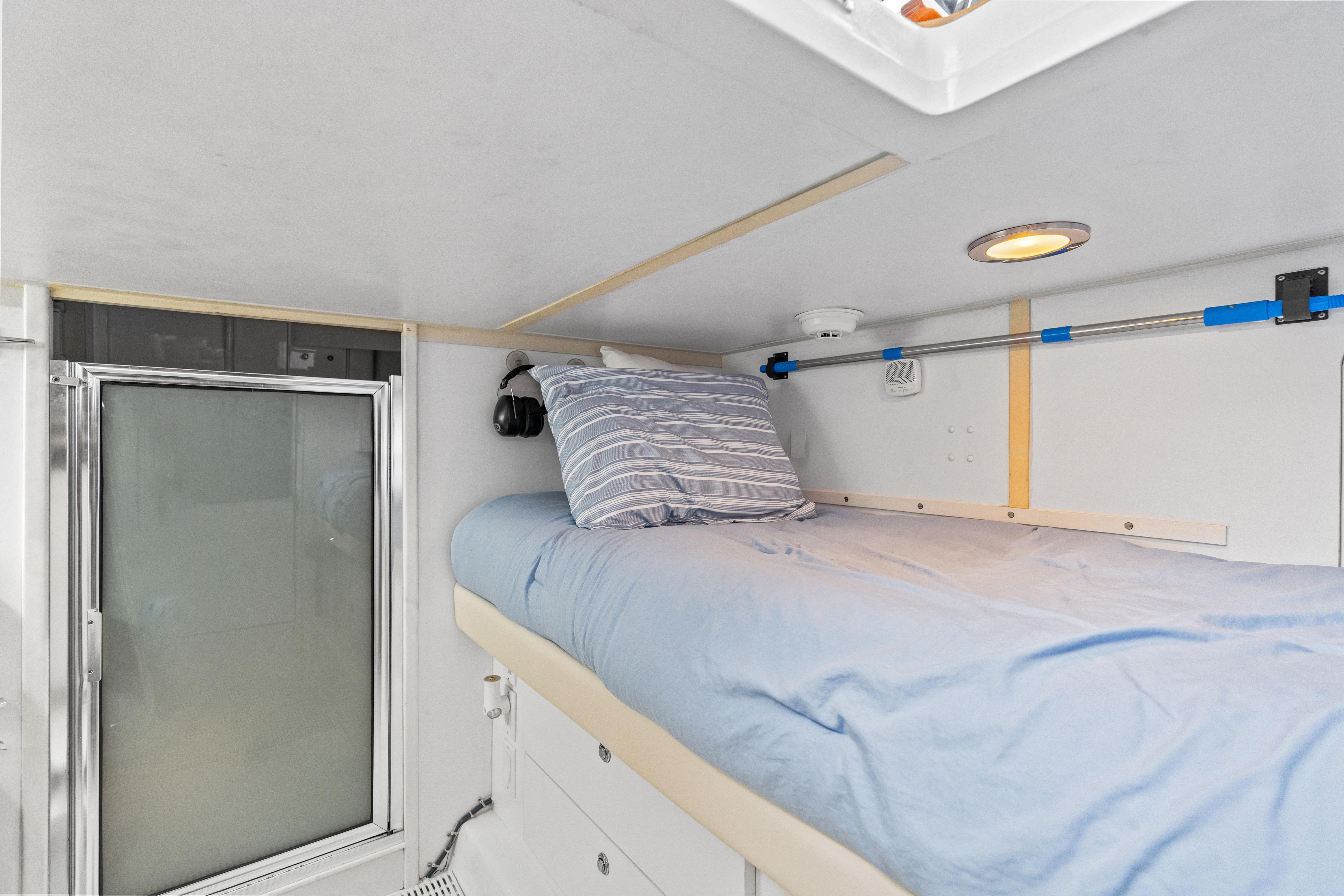 Cozy cabin bed in 2008 Hatteras 64 Motor Yacht with blue bedding and striped pillow.