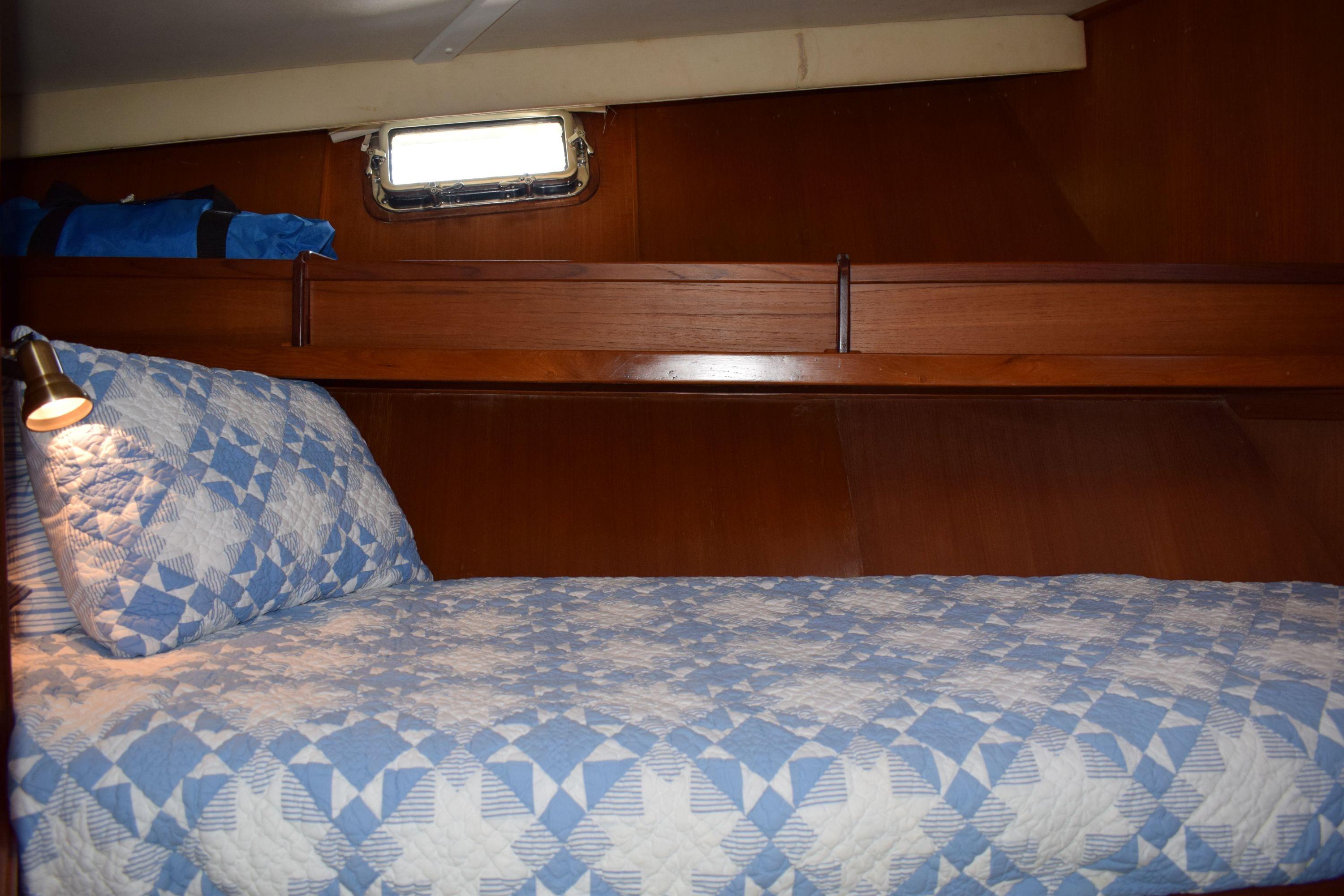 Cozy cabin interior of 1980 Cheoy Lee 52 Motorsailer with quilted bedding and wooden finish.