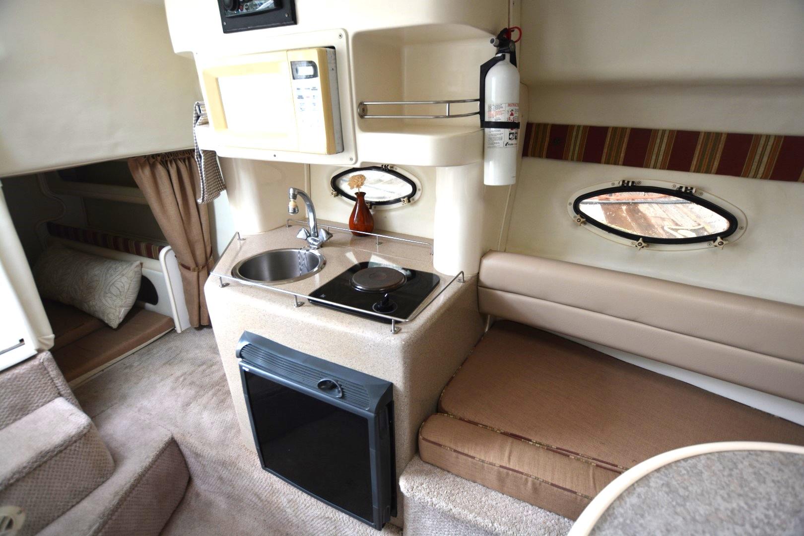1999 Rinker 270 Fiesta Vee cabin interior with kitchenette, seating, and sleeping area.