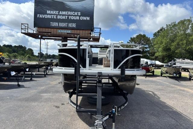 2026 Sun Tracker Fishin' Barge 22 DLX on trailer, outdoor display under billboard.